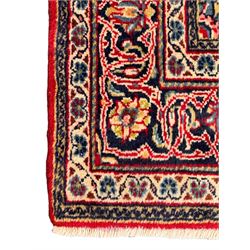 North west Persian Sarouk crimson ground rug, central floral medallion surrounded by scrolling branches decorated with foliage and stylised plant motifs, the main border decorated with repeating scrolling design with floral motifs, within guard stripes 