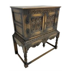 Jacobean Revival carved oak cupboard, moulded rectangular top over S-scroll carved frieze and two doors, the panelled doors carved with stylised plant motifs, on stand decorated with lunettes and shaped apron with hanging turned pendant, on turned supports united by stretchers 