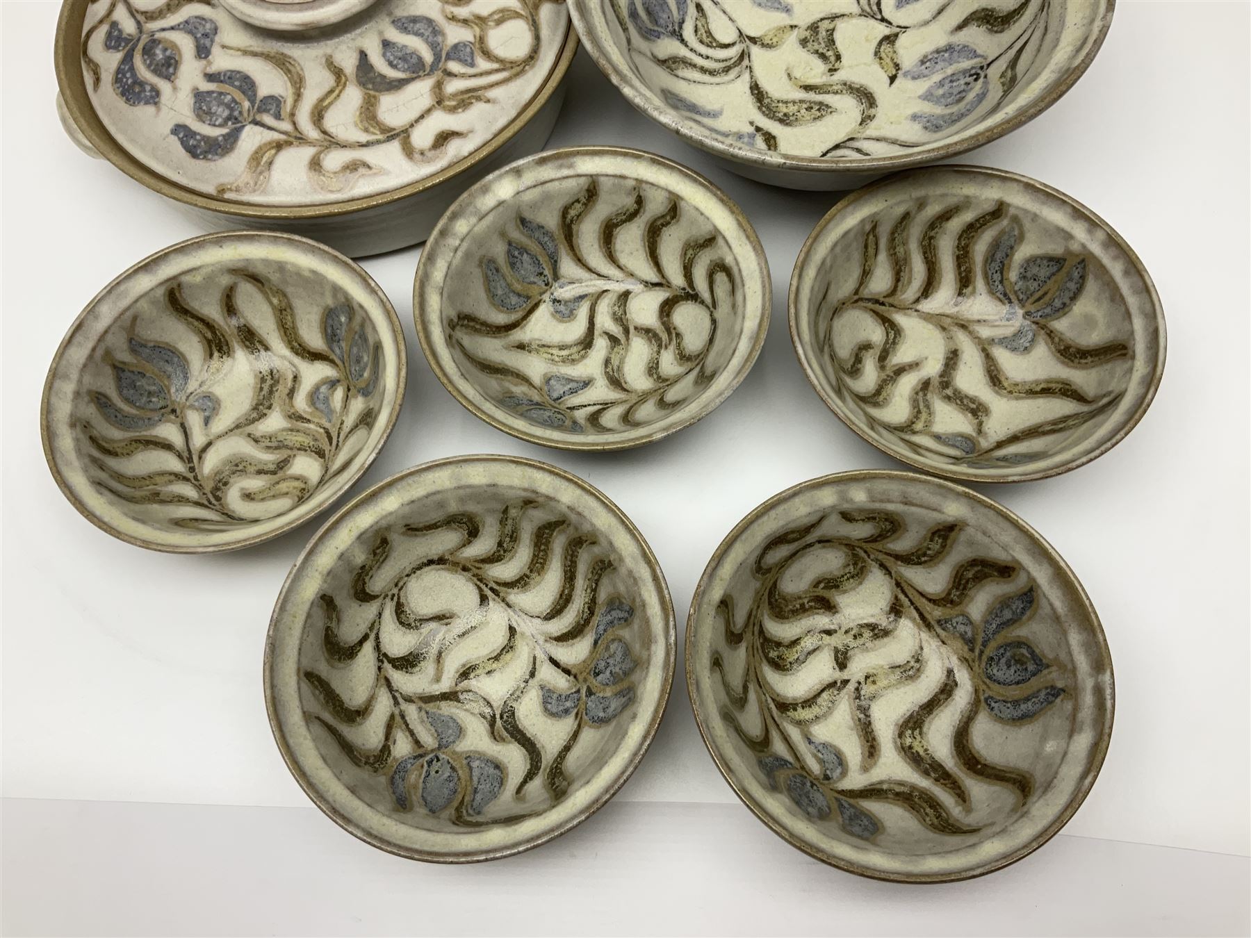 John Egerton (c1945-): studio pottery stoneware, comprising twin shallow covered dish, serving bowl and eight dessert bowls, all decorated with flowering sprigs on a cream ground, dish D28cm