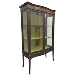 Edwardian inlaid mahogany serpentine display cabinet, projecting moulded cornice over figured frieze inlaid with tailing bellflowers and central fan motif, enclosed by two glazed doors, on square tapering supports with splayed terminals 