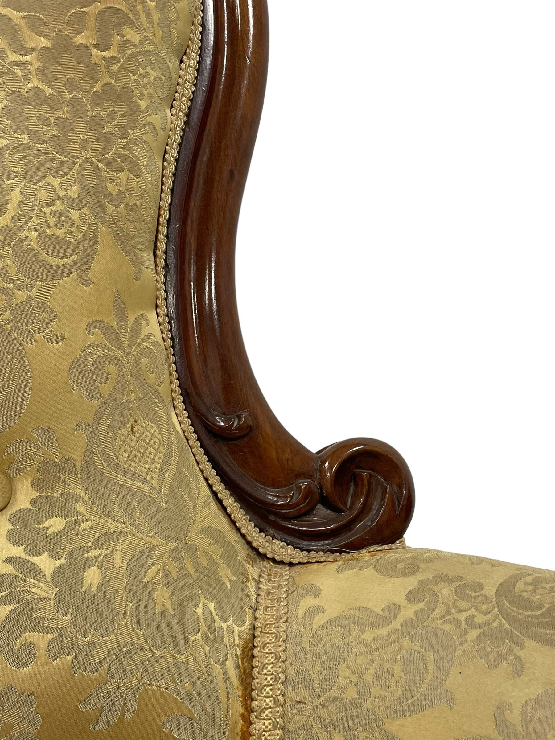 Victorian mahogany framed armchair, shaped and moulded frame carved with curled foliage, upholstered in pale gold floral pattern silk damask fabric, scrolled arm terminals on shaped moulded supports terminating to scroll carved feet