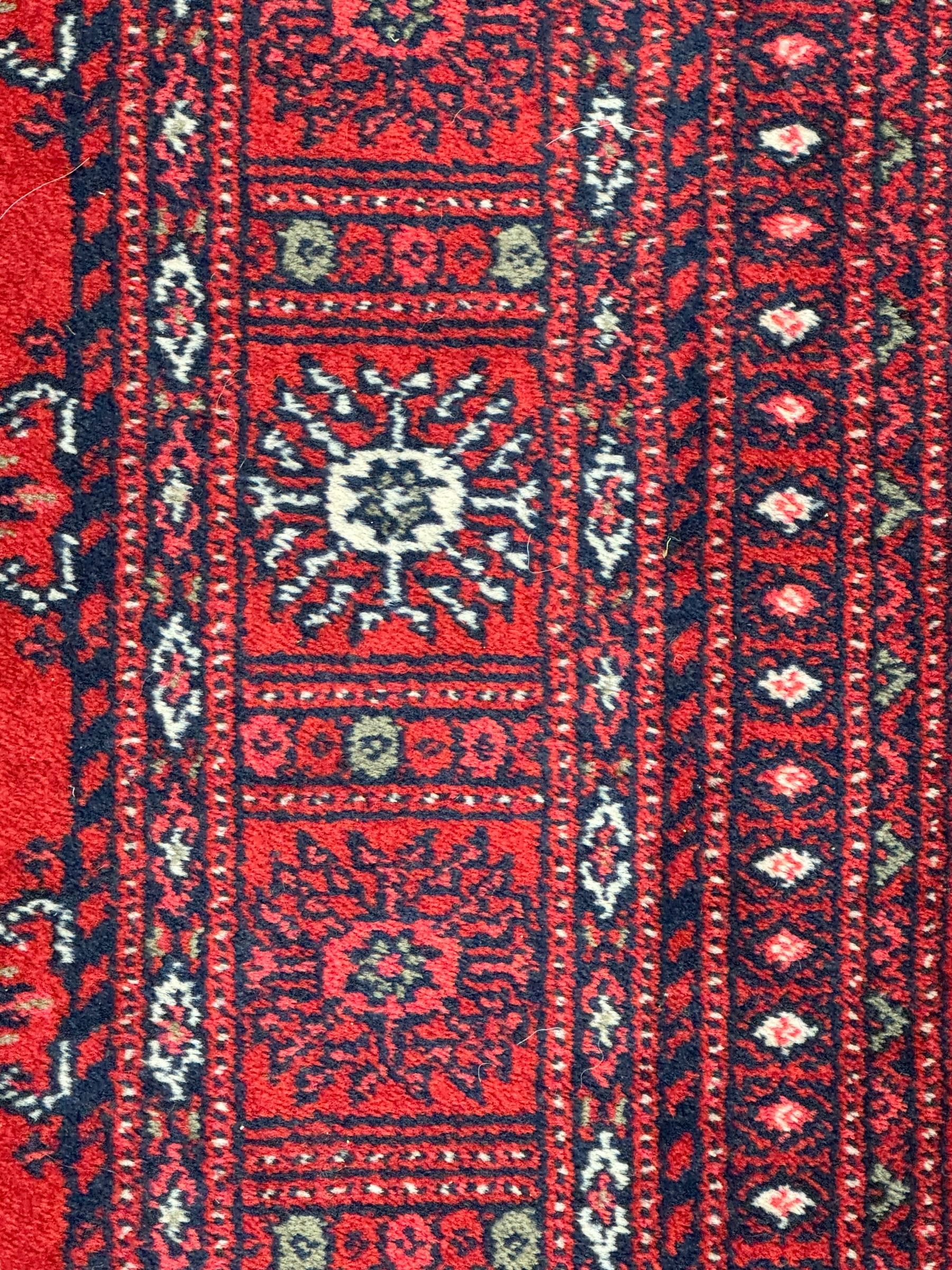 Persian Bokhara crimson ground runner rug, the field with a series of repeating ivory octagonal medallions, main border with repeating flower head pattern and diamonds within multiple guard stripes