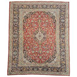 Persian Kashan crimson ground carpet, floral design central medallion surrounded by trailing leafy branches and stylised plant motifs, multi-band border with repeating floral design