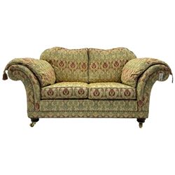 Traditional design two seat sofa, high back with scrolled arms, upholstered in beige fabric with red and green damask motifs, on castor supports (L178cm, D100cm, H89cm); matching armchair (L109cm, D89cm, H89cm)