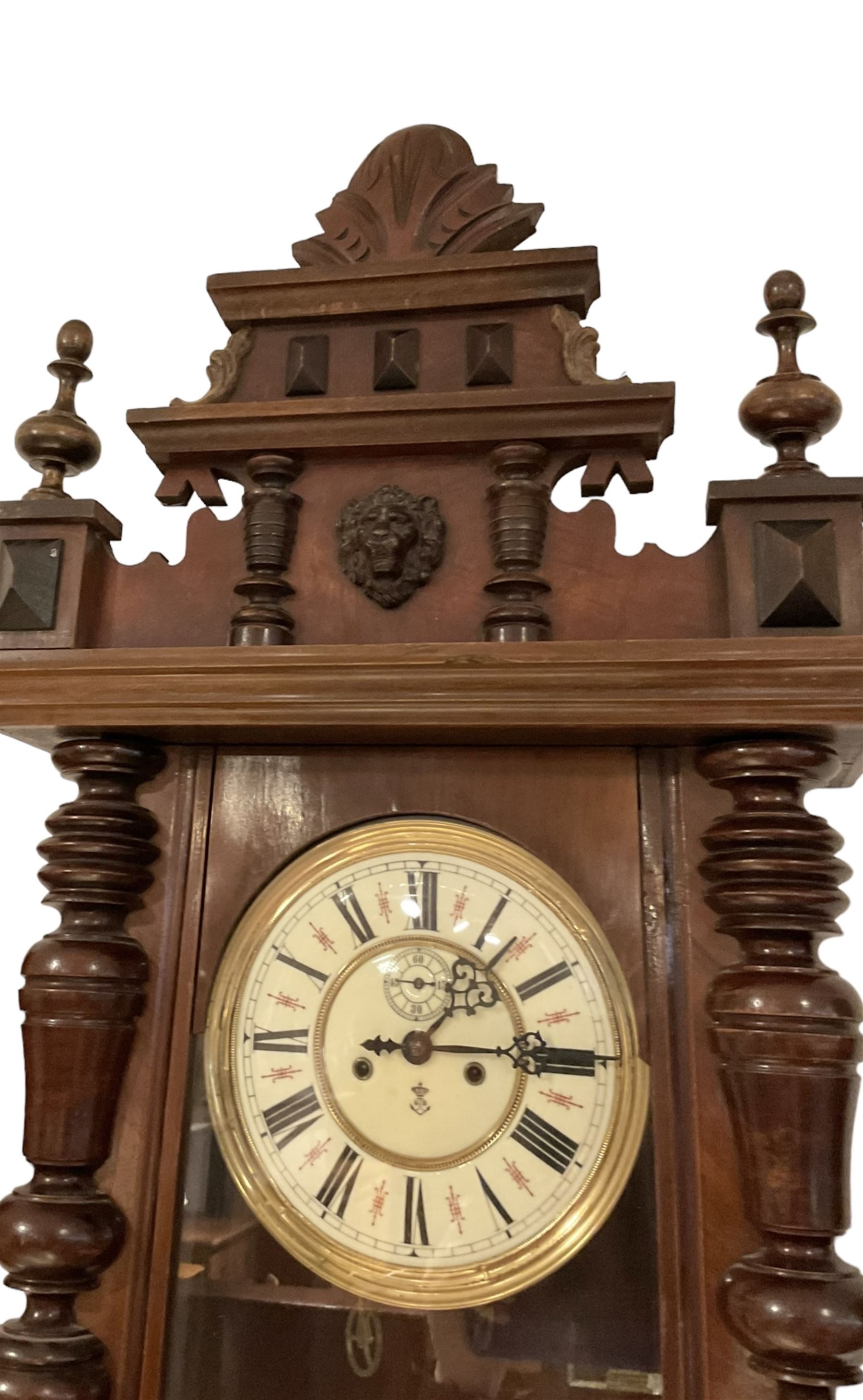 Gustav Becker -  German weight-driven 8-day wall clock in a walnut and ebonised case with a carved pediment and finials, fully glazed case door with visible pendulum and two brass cased weights, two  part dial with seconds hand, Roman numerals and pierced steel hands, rack striking movement with a deadbeat escapement.