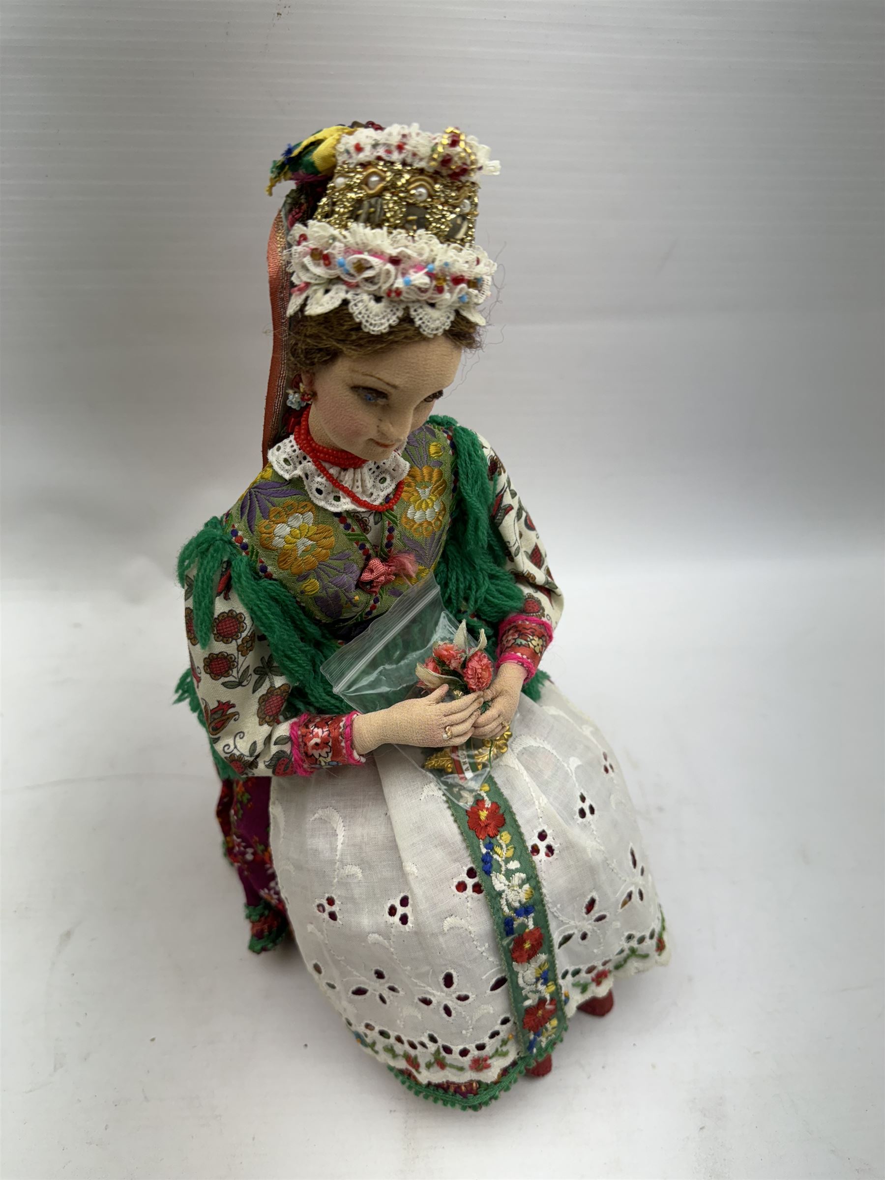 Anna Meszaros (Hungarian 1905-1998): Young Woman Holding Flowers, handmade needlework figurine, together with two badges awarded to the artist in needlework competitions, figure H29cm
Auctioneer's Note: Anna Meszaros came to England from her native Hungary in 1959 to marry an English businessman she met while demonstrating her art at the 1958 Brussels Exhibition. Shortly before she left for England she was awarded the title of Folk Artist Master by the Hungarian Government. Anna was a gifted painter of mainly portraits and sculptress before starting to make her figurines which are completely hand made and unique, each with a character and expression of its own. The hands, feet and face are sculptured by layering the material and pulling the features into place with needle and thread. She died in Hull in 1998