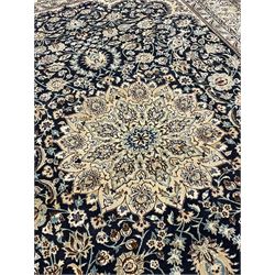 Persian Kashan indigo ground carpet, the central ivory rosette medallion surrounded by trailing and interlaced flower heads and branches, matching spandrels with floral design, the border with scrolling pattern decorated with stylised plant motifs within guards