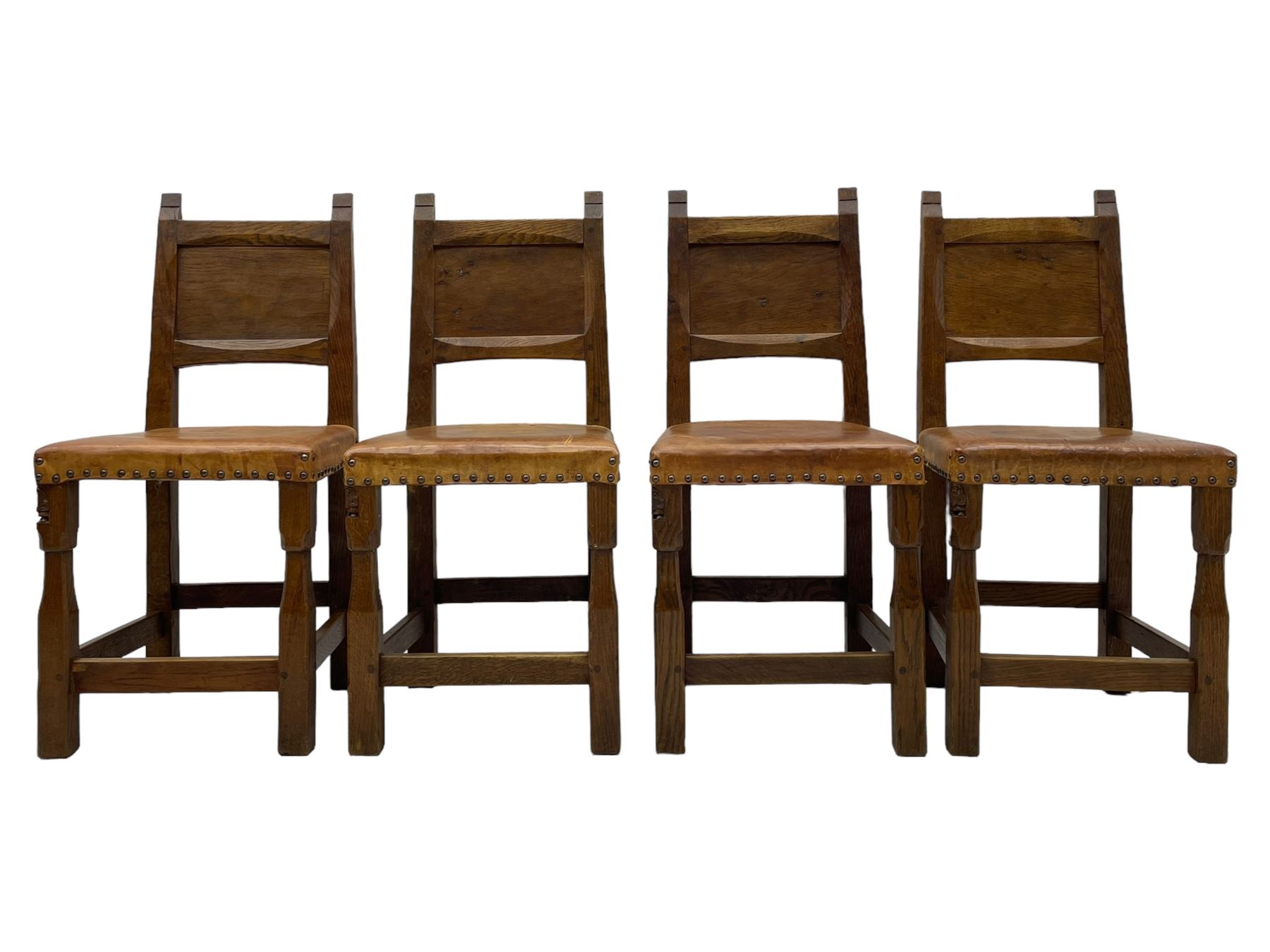 Gnomeman - set of eight (6+2) oak dining chairs, adzed panelled back over tan leather upholstered seat with applied stud band, on square supports united by plain stretchers, each chair carved with gnome signature, by Thomas Whittaker, Littlebeck, Whitby