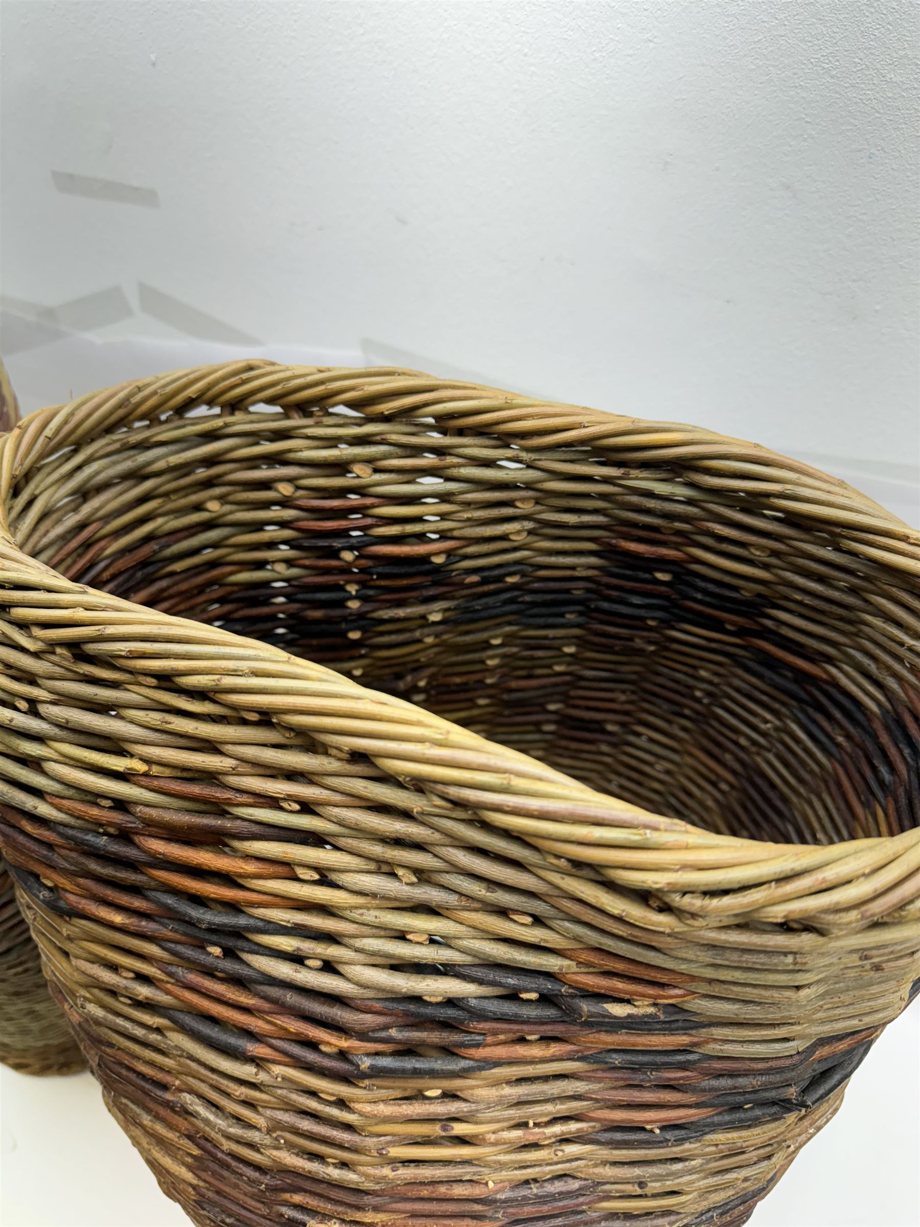 Two rattan baskets, of circular abstract form, together with two crook walking stick, basket H62cm 