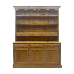 Traditional design waxed pine dresser, upper section with moulded cornice over scalloped frieze, fitted with two open shelves and four drawers, lower section with three drawers over three panelled cupboards, on plinth base