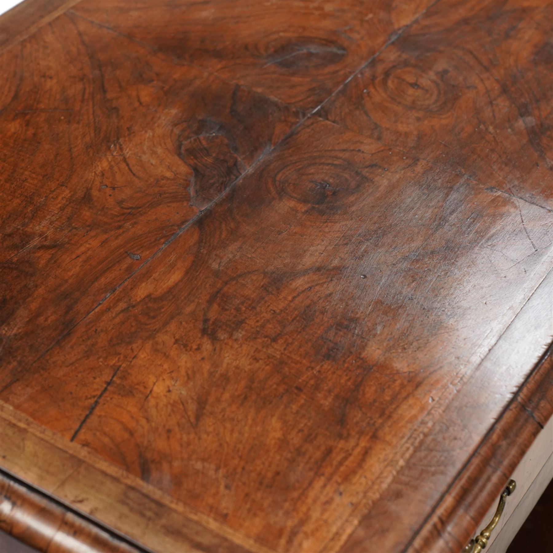 George II figured walnut knee-hole desk, the rectangular quarter-matched veneer top with moulded edge, crossbanding and feathered-banding, fitted with single frieze drawer over three drawers to each side, each with the central recess fitted with a single cupboard enclosing shelf, lower moulded edge on bracket feet