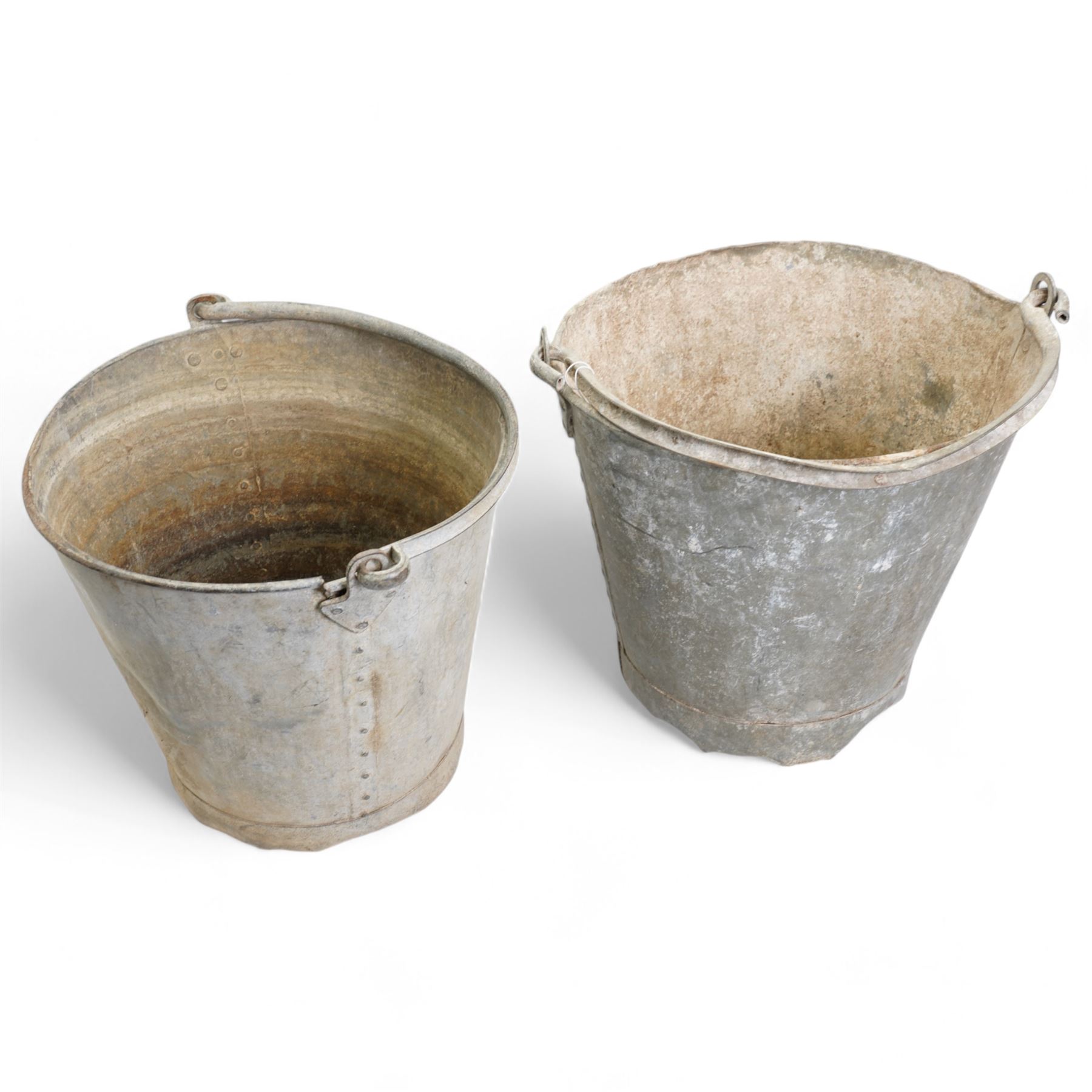 Two galvanised tin buckets, of conical riveted form with swing handles, H30cm