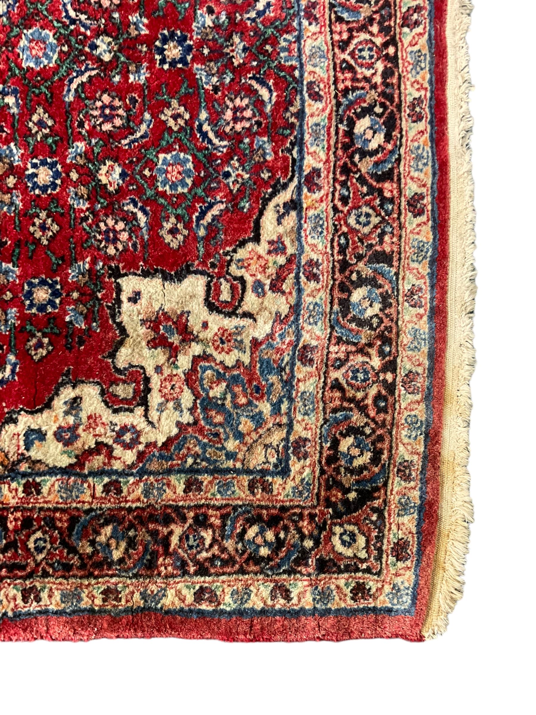 Persian design crimson ground rug, the field decorated with central floral pole medallion and surrounded by foliate patterns with matching spandrels, guarded border with repeating palmette motifs