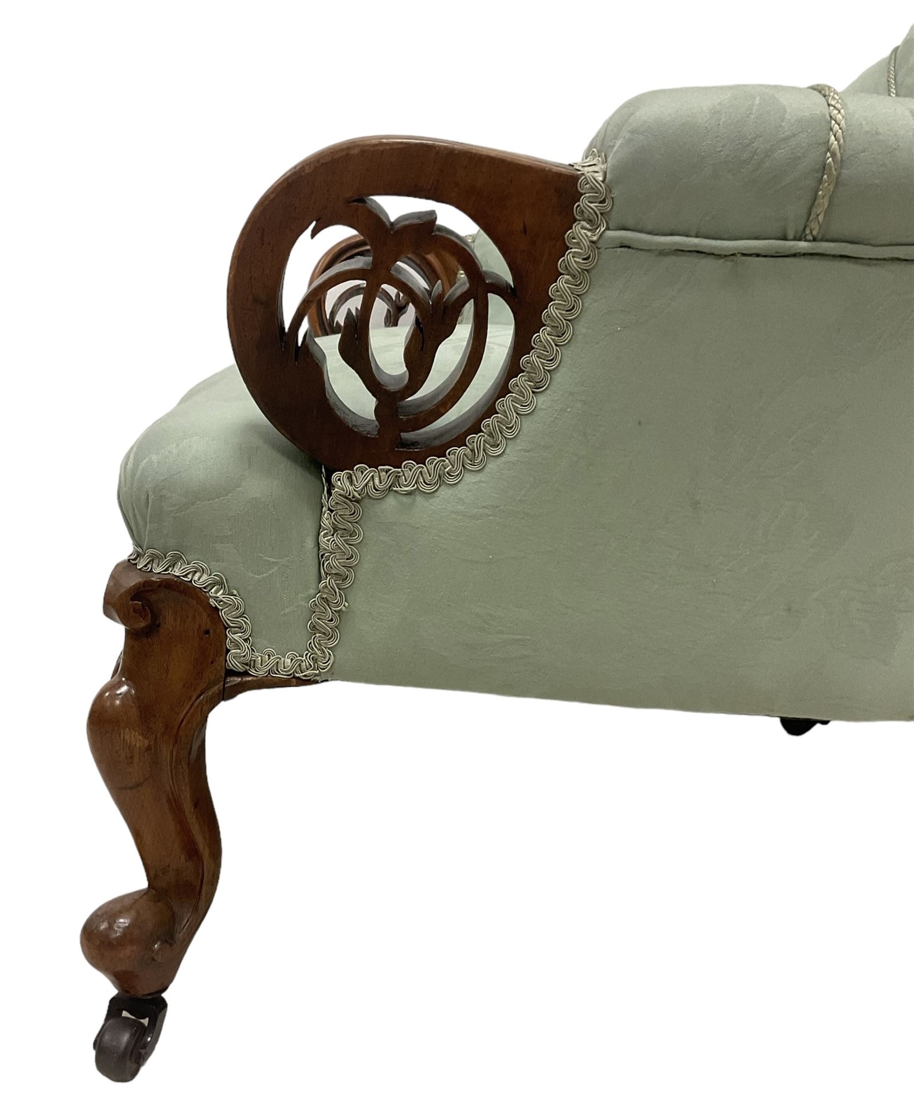 19th century mahogany framed fan-back armchair, upholstered in buttoned turquoise floral damask fabric with spring seat and pearlescent piping, pierced and carved arm terminals with floral motif, over serpentine fronted seat, raised on cartouche carved cabriole supports with castors