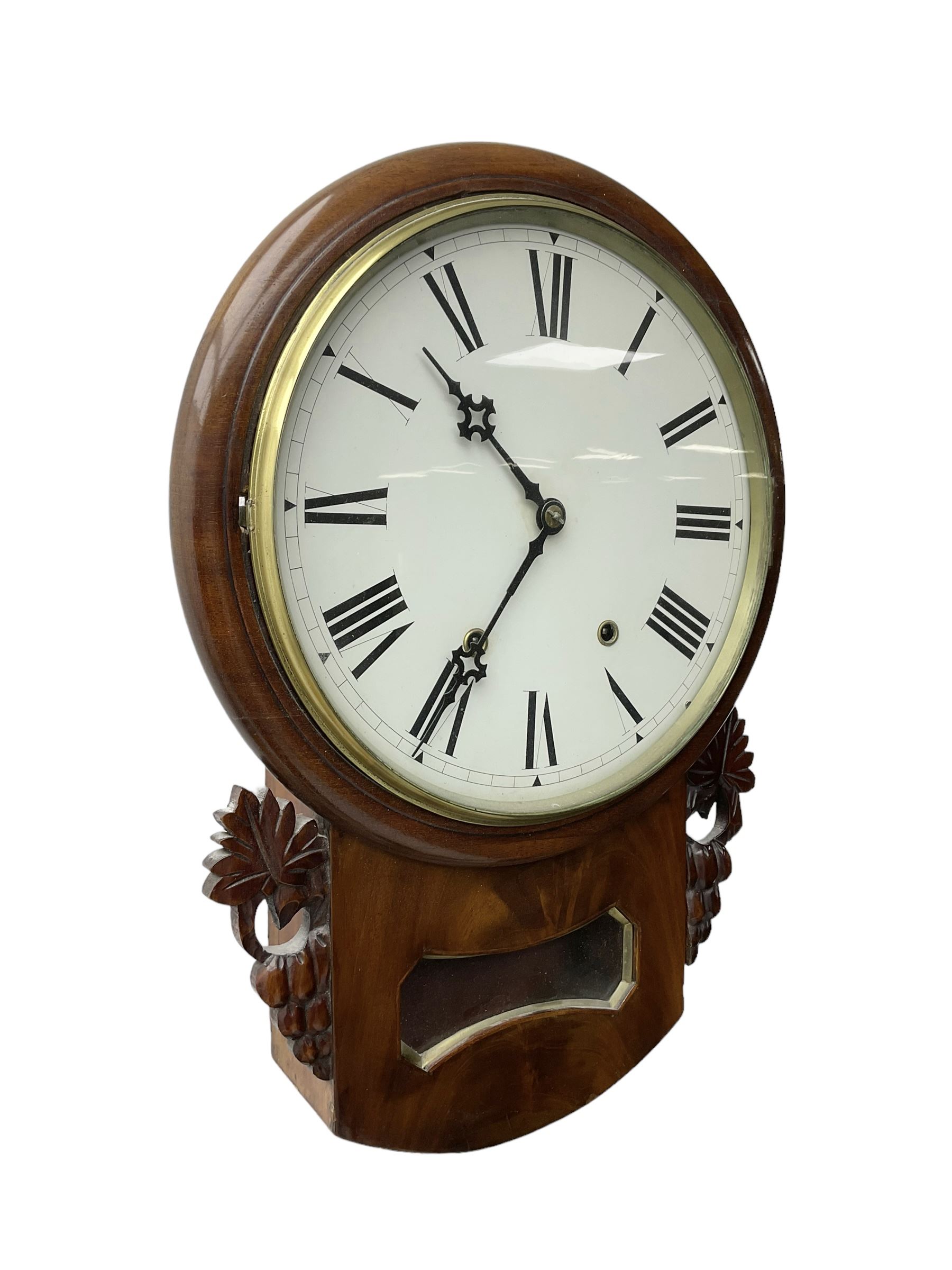 Late 19th century 8-day  drop dial wall clock in a mahogany case, carved ear pieces and glazed pendulum viewing glass, 12” painted dial with Roman numerals and Maltese steel hands, twin train going barrel movement striking the hours on a bell. No pendulum or key.