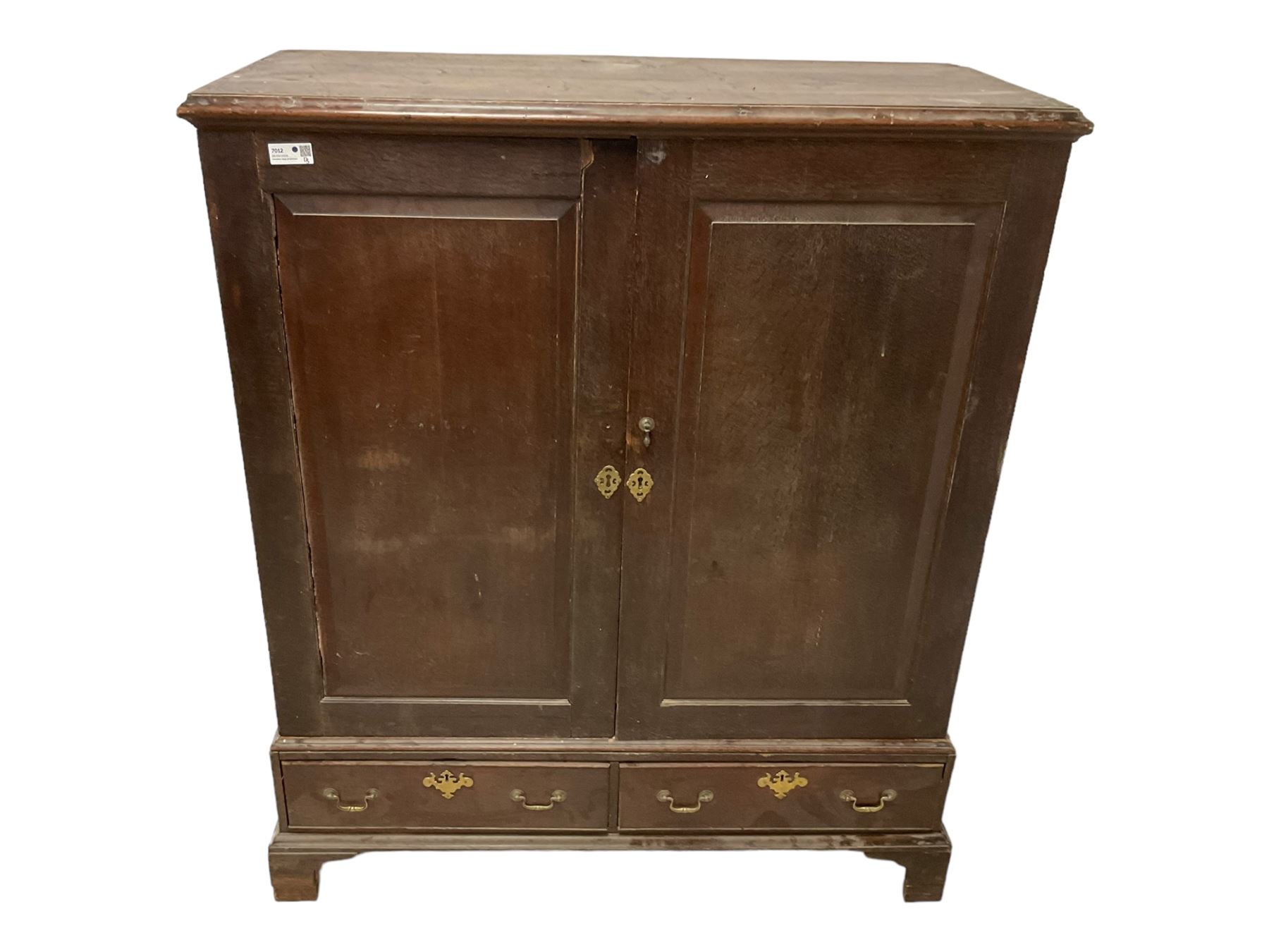 18th century oak linen press, moulded cornice over two panelled cupboard doors, the base fitted with two cock-beaded drawers with pieced brass escutcheons and handles, lower moulded edge on bracket feet