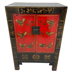 20th century Chinese black lacquered cabinet, rectangular body with two doors enclosing single shelf interior, adorned with gilt butterfly and floral motifs against a red backdrop, standing on square supports