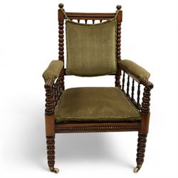 Late Victorian walnut bobbin turned armchair, curved cresting rail with bead moulding over turned spindle back, upholstered arms on turned balustrade supports, cane work seat over seat rail with matching bead moulding, loose seat cushion upholstered in olive green fabric, on tapering bobbin turned front supports with brass and ceramic castors, 