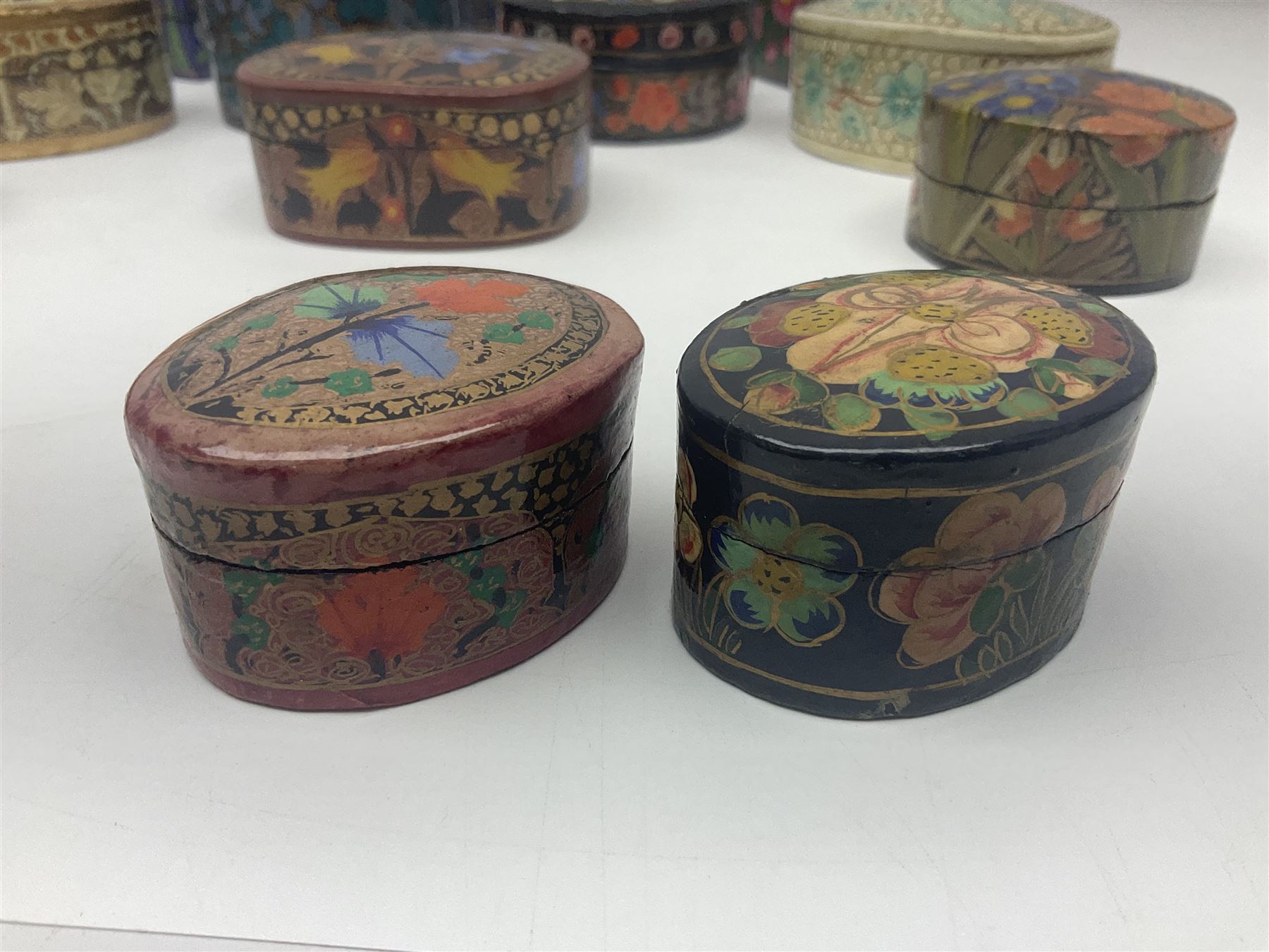 Twelve lacquered boxes, to include square and oval examples, with floral decorations, tallest H5cm