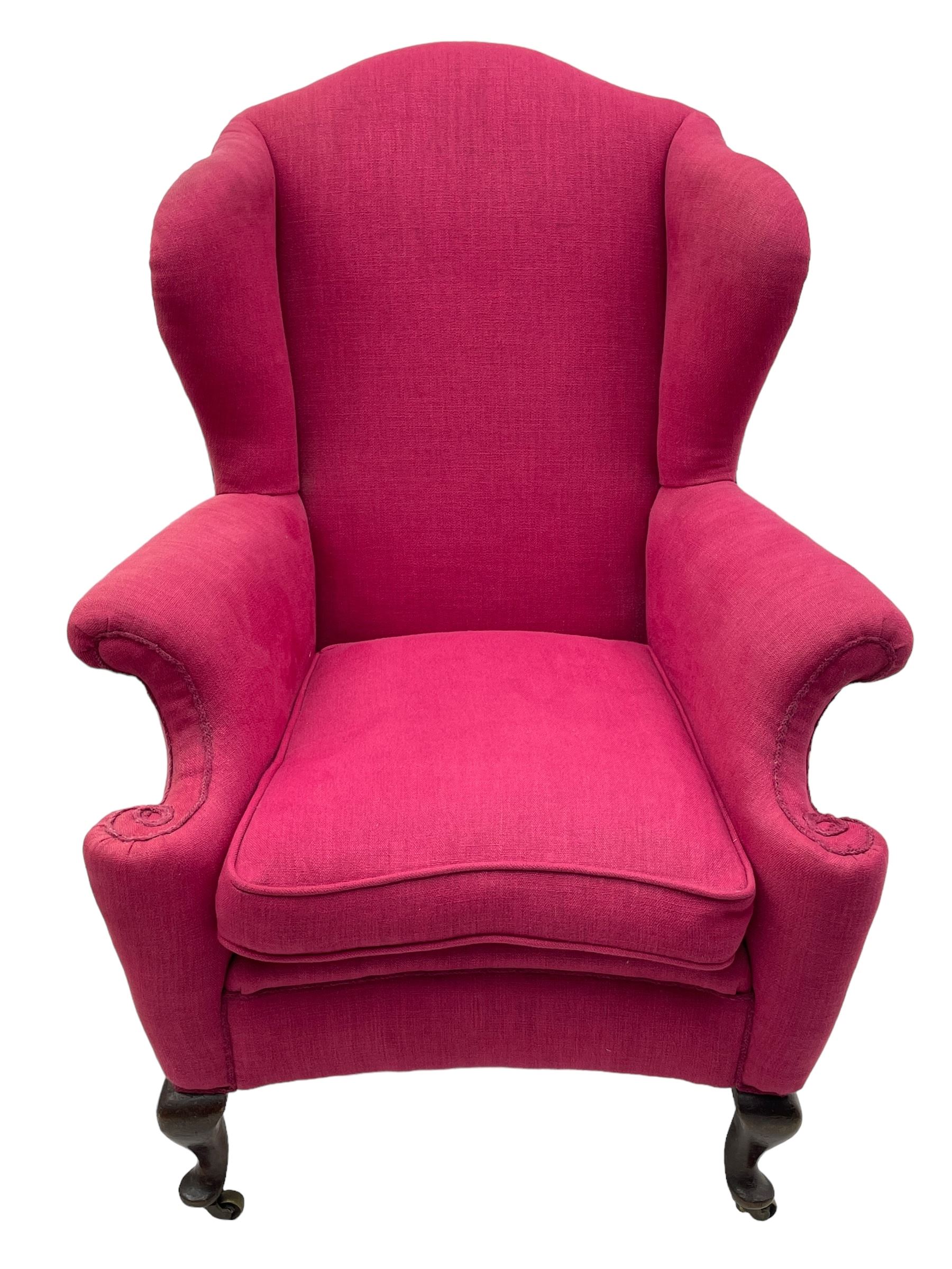 Georgian design hardwood-framed wingback armchair, arched cresting rail over curved wingback, rolled arms on scrolled cushioned supports, reverse bow-front, upholstered in claret red fabric with loose seat cushion, on cabriole front feet and brass castors 