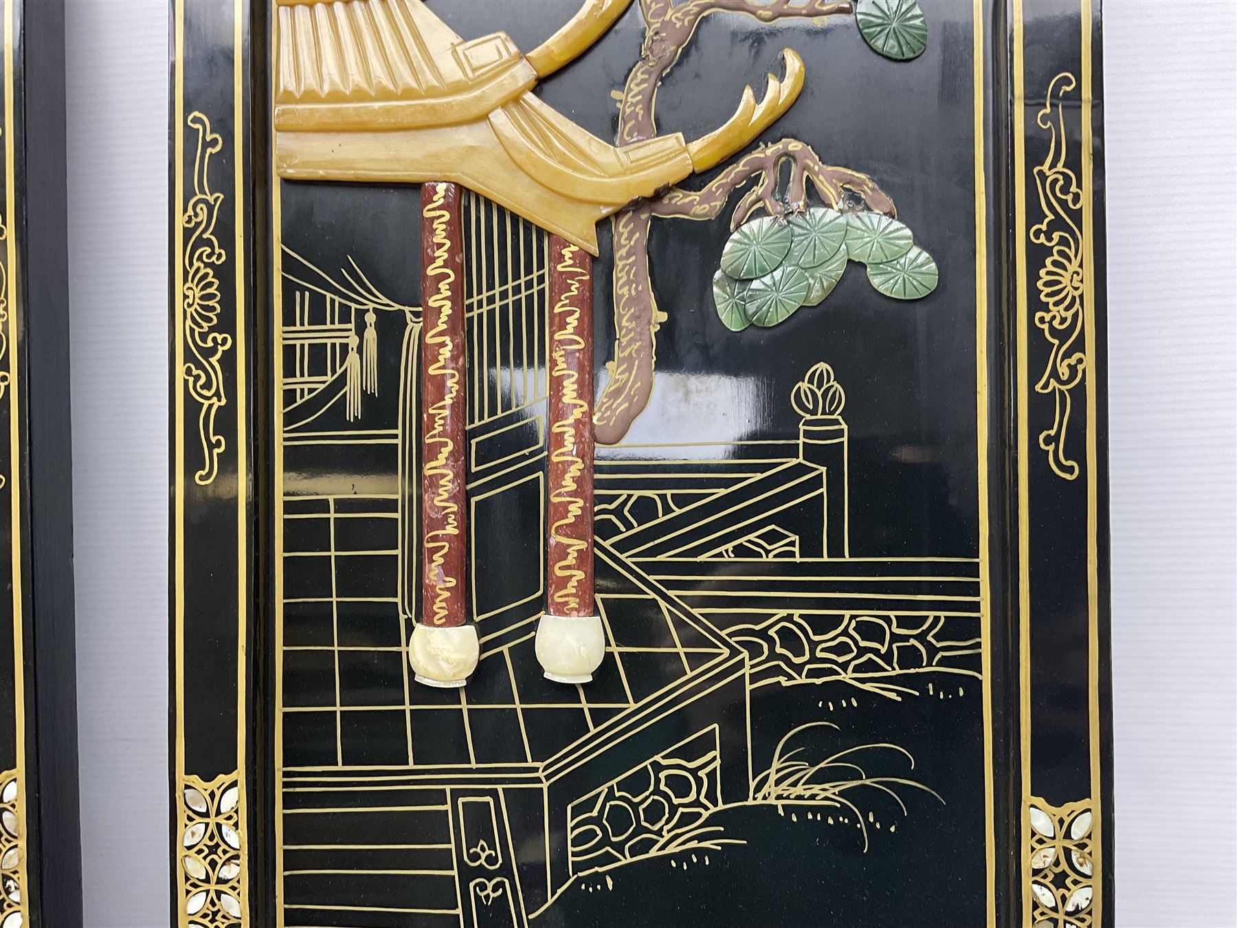 Two 20th century Chinese lacquered wall plaques, decorated in relief with female figures playing instruments beneath a pagoda, within gilt and mother of pearl inlaid borders, H92cm