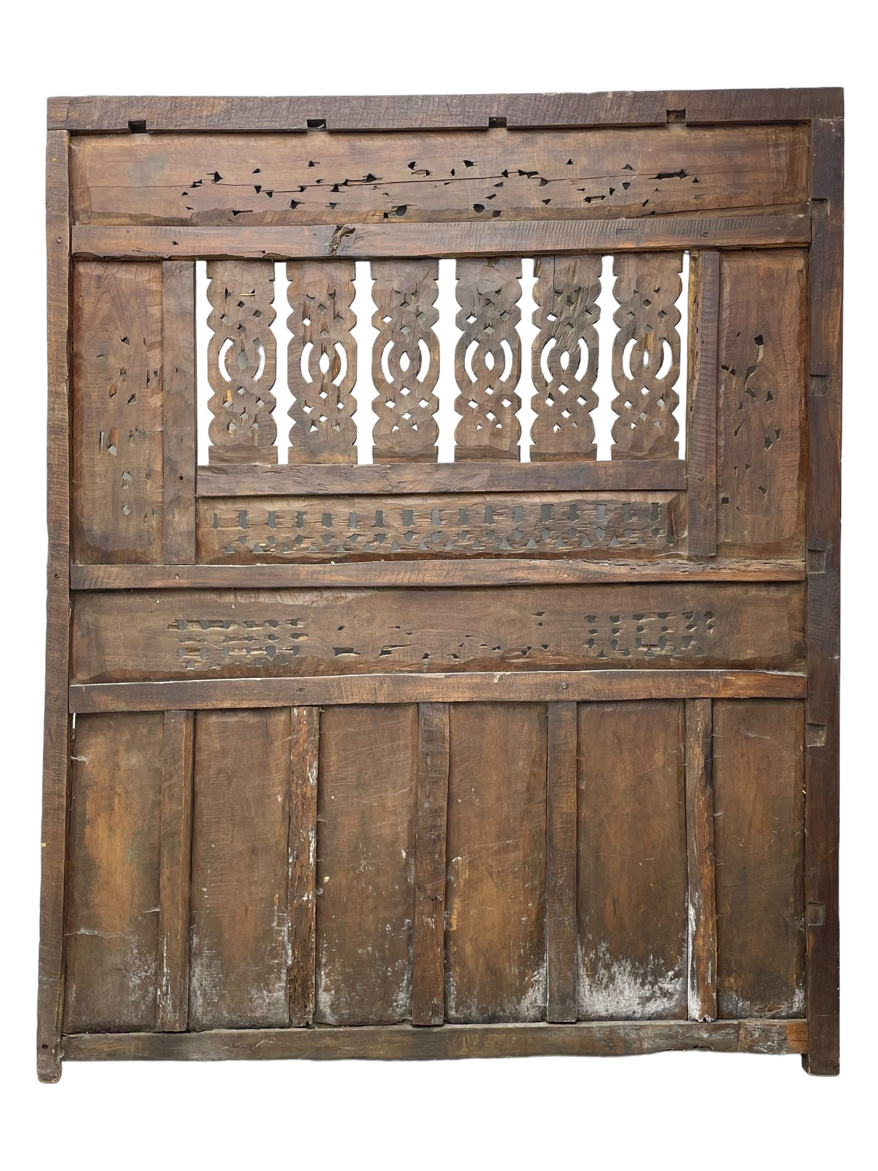 Early 20th century Javanese teak and hardwood door panel or room divider, rectangular panelled form with moulded frame and pegged construction, carved and pierced with scrolling decoration and flower head motifs, shaped and pierced splats with interlocking pattern