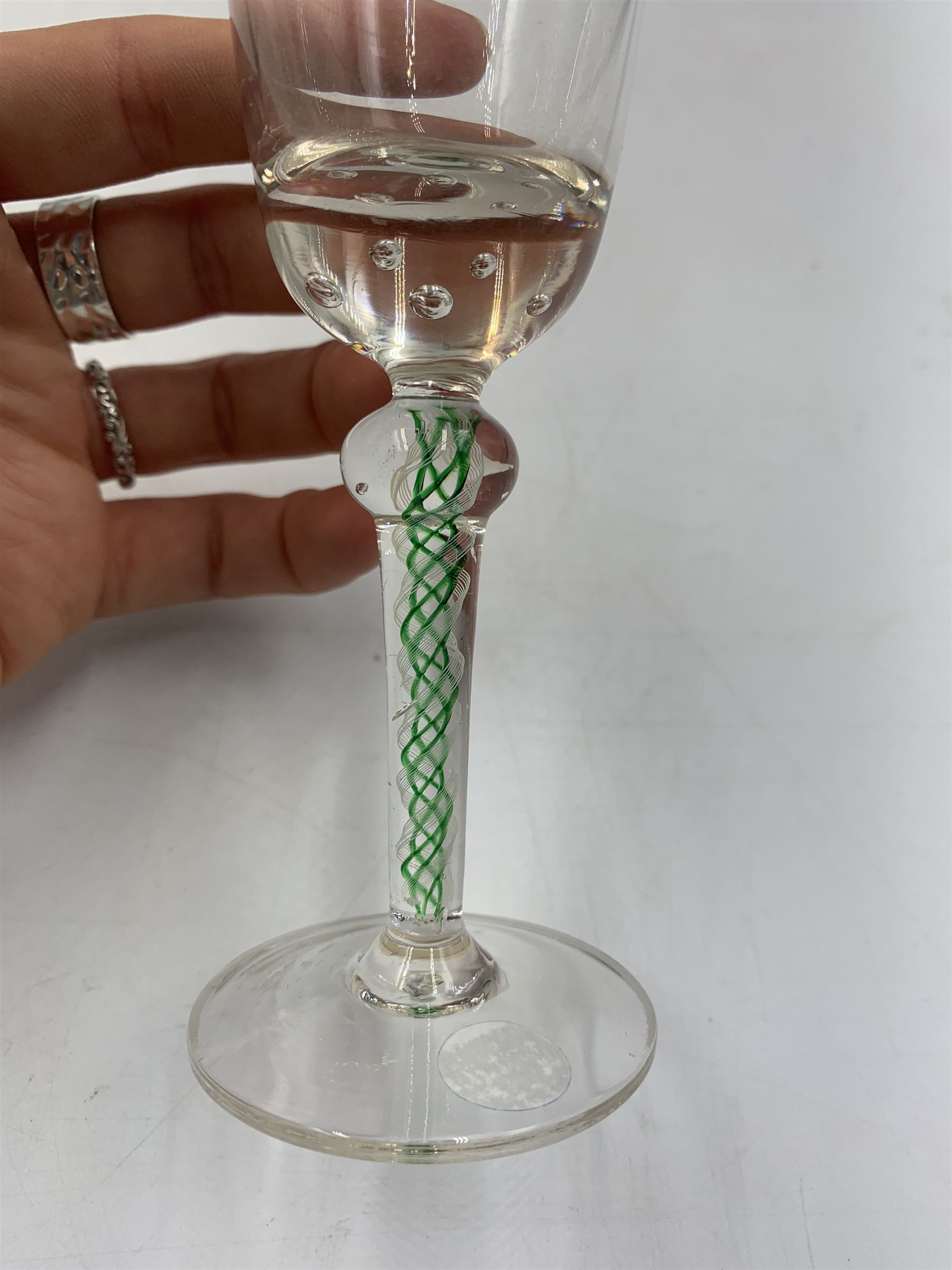 19th century continental liqueur glass, circa 1870, bucket bowl with bubble decoration, the tapered stem with green and white strands, H12.5cm; together with a Victorian aperitif glass, trumpet bowl decorated with foliate and fruiting vines, H10cm (2)