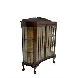 Early 20th century mahogany serpentine display cabinet, raised back carved with foliate scrolls, enclosed by two glazed doors, on ball and claw cabriole feet