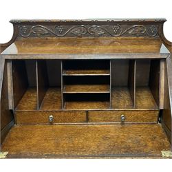 Early 20th century heavily carved oak bookcase bureau, raised back with grape-vine carved frieze, over fall-front enclosing fitted interior, above two short drawers and curved frieze drawer, flanked by astragal glazed and panelled cupboards, on turned feet