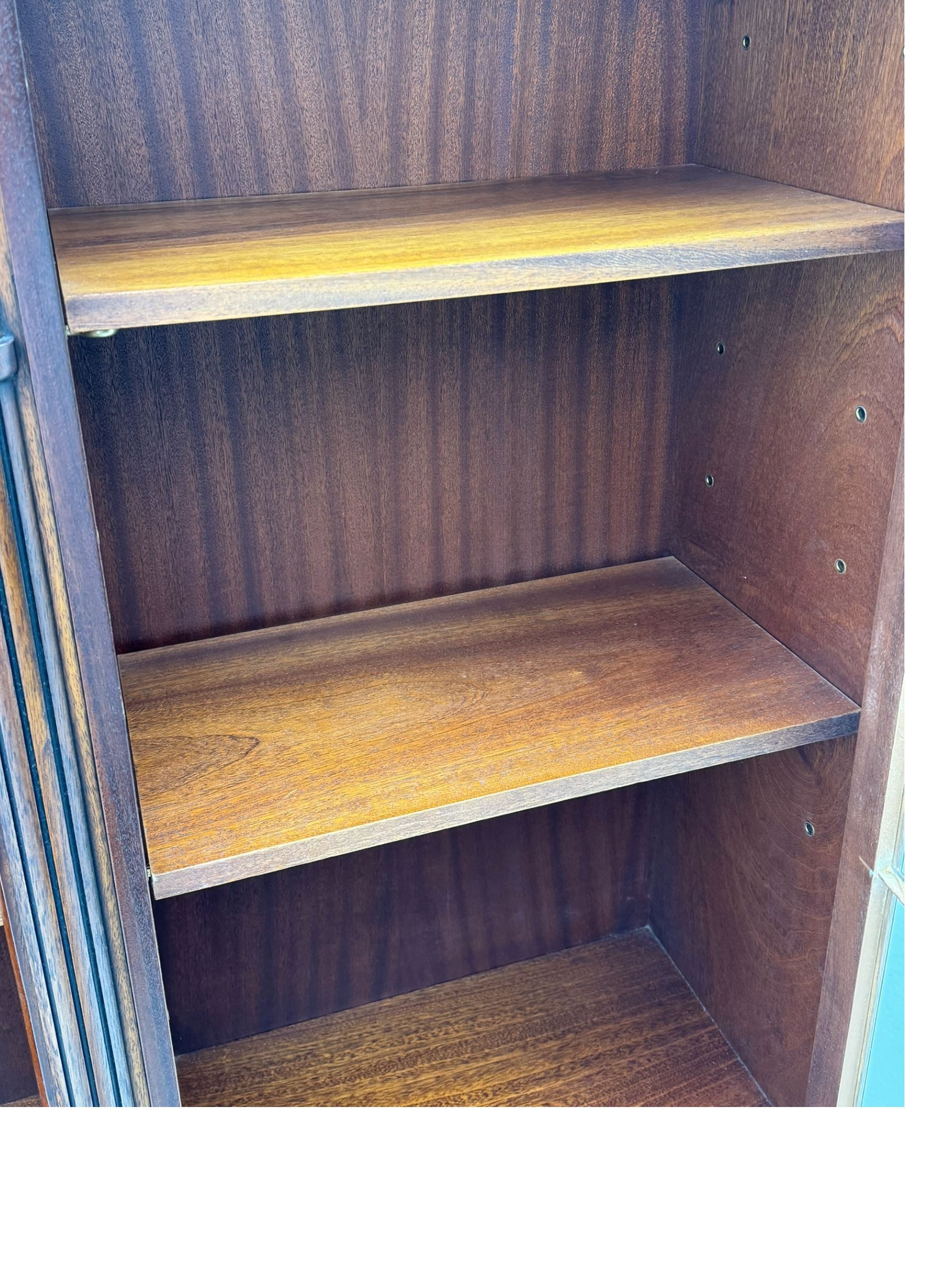 Georgian design mahogany bookcase on cupboard, projecting moulded and dentil cornice, two display cabinets enclosed by glazed doors above over three drawers and three cupboards, on bracket feet