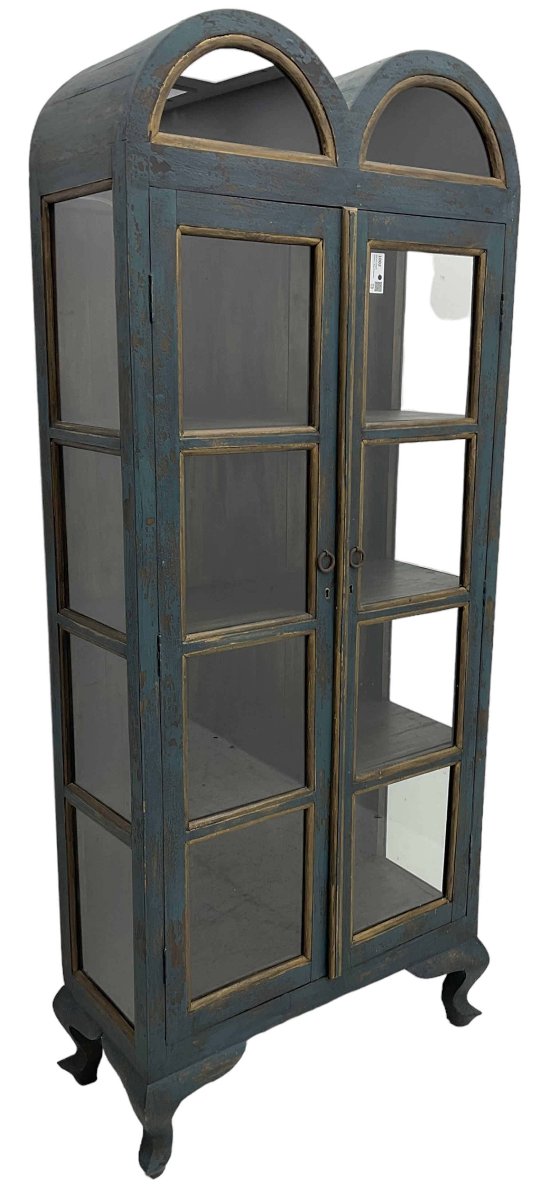 Tall painted glazed display cabinet, double arched top over two glazed doors, fitted with three shelves, in rustic blue paint finish, on cabriole feet