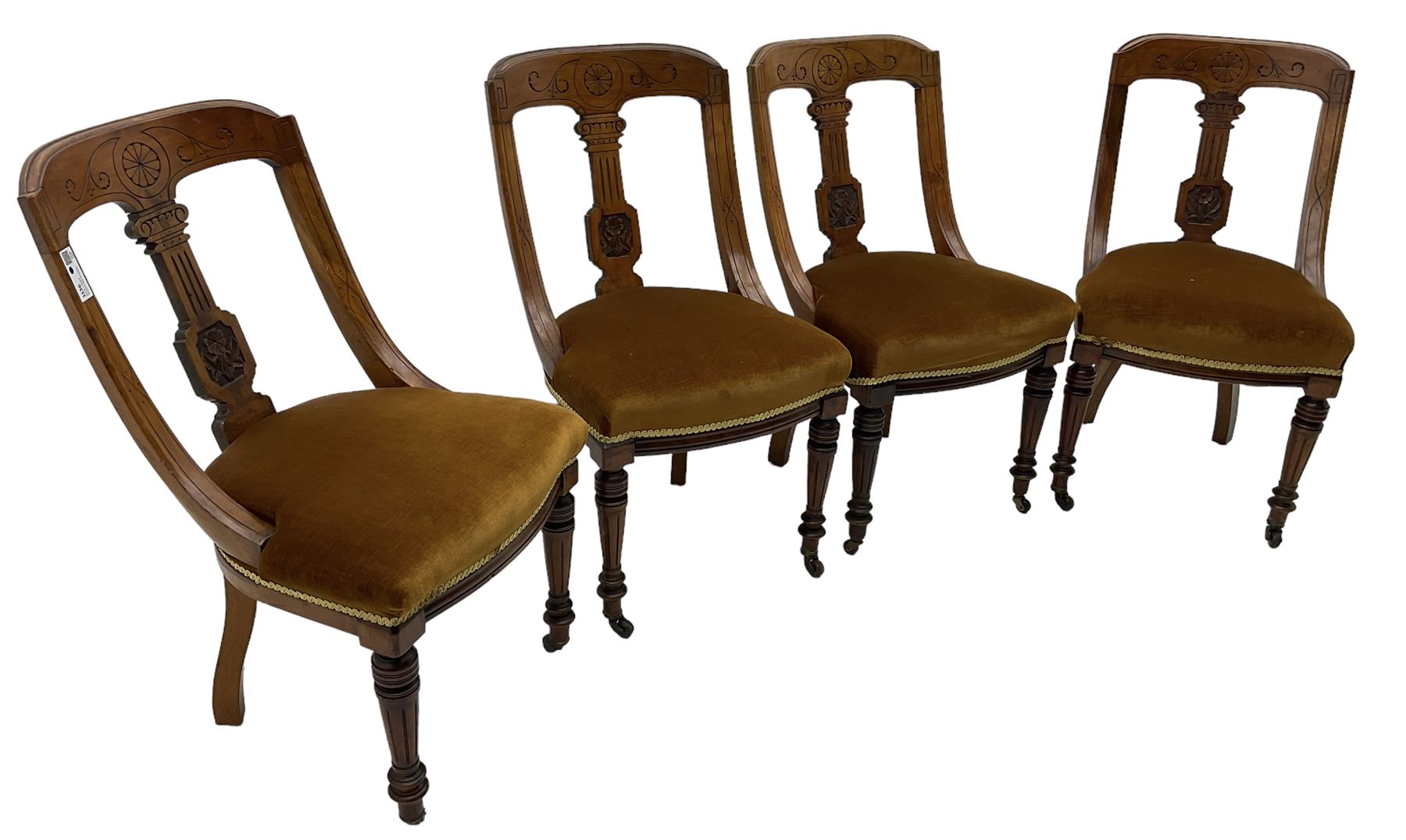 Set of four late Victorian walnut dining chairs, carved with stylised floral decoration and scrolling branches, upholstered seat, on turned and fluted supports 