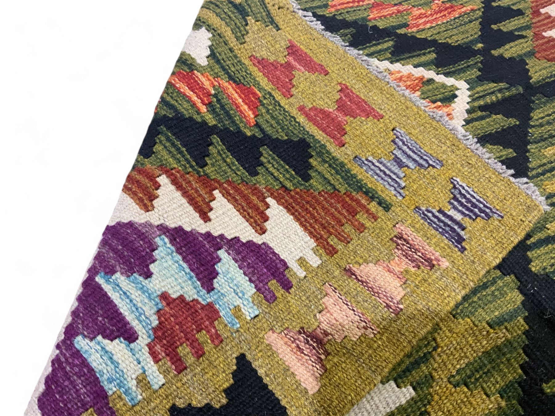 Chobi kilim multi-coloured rug, the field decorated with various lozenges with dark indigo borders, enclosed by a guard band with repeating broken-lozenge design