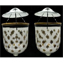 India Jane Interiors - pair of glass hanging lanterns, clear glass bell jars decorated with gold starburst patterns, each topped with a wide glass dish and suspended by three brass chains, the rim of each bell jar accentuated with a brass band, black metal hooks with a dragon head motif attach the chains to the rim