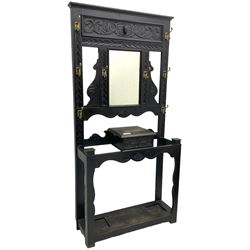 Victorian oak hall stand, the upper section featuring eight brass hooks and central mirror plate flanked by scroll-carved panels, the central section includes a storage box positioned above an umbrella stand, supported by square carved legs with scroll-carved horizontal supports