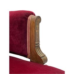 Late Victorian inlaid walnut two seat settee, the shaped cresting rail decorated with foliate inlays and boxwood stringing, upholstered in crimson velvet with sprung seat, raised on turned and fluted supports with ceramic castors