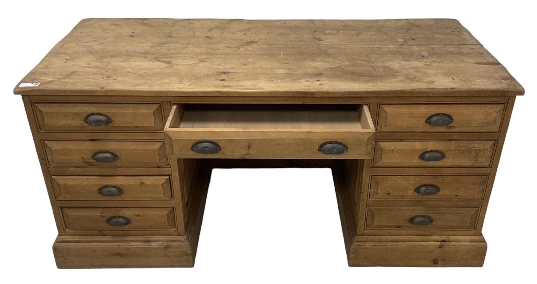 20th century waxed pine kneehole desk, rectangular top over nine drawers with cup handles, on moulded plinth base