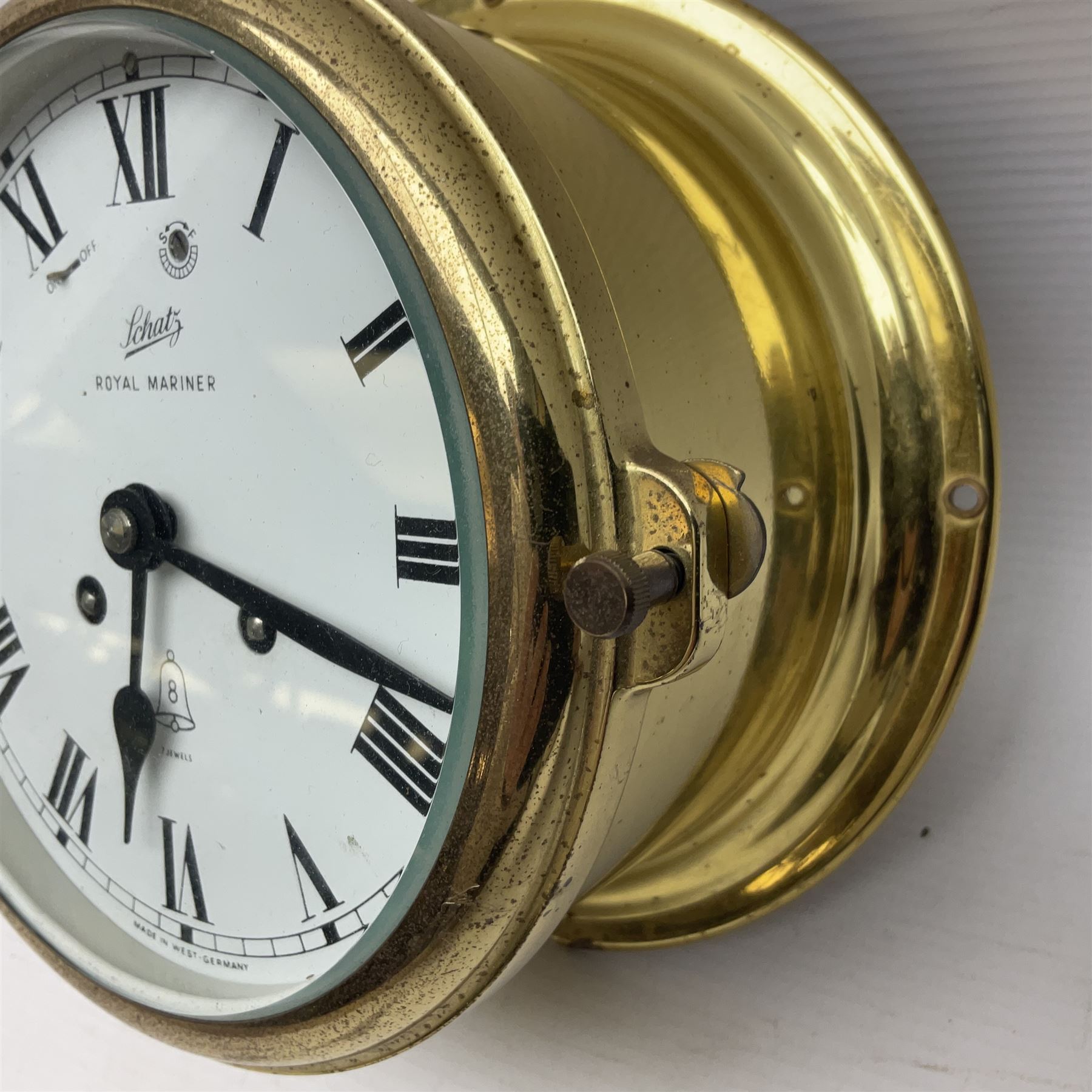 German Schatz Royal Mariner bulkhead ships clock, with an eight-day two-train platform seven-jewel movement, striking the ship's watch on a bell, with bells on/off facility and platform regulation on the 5 inch painted dial, with roman numerals and minute track, in brass case, case D16cm