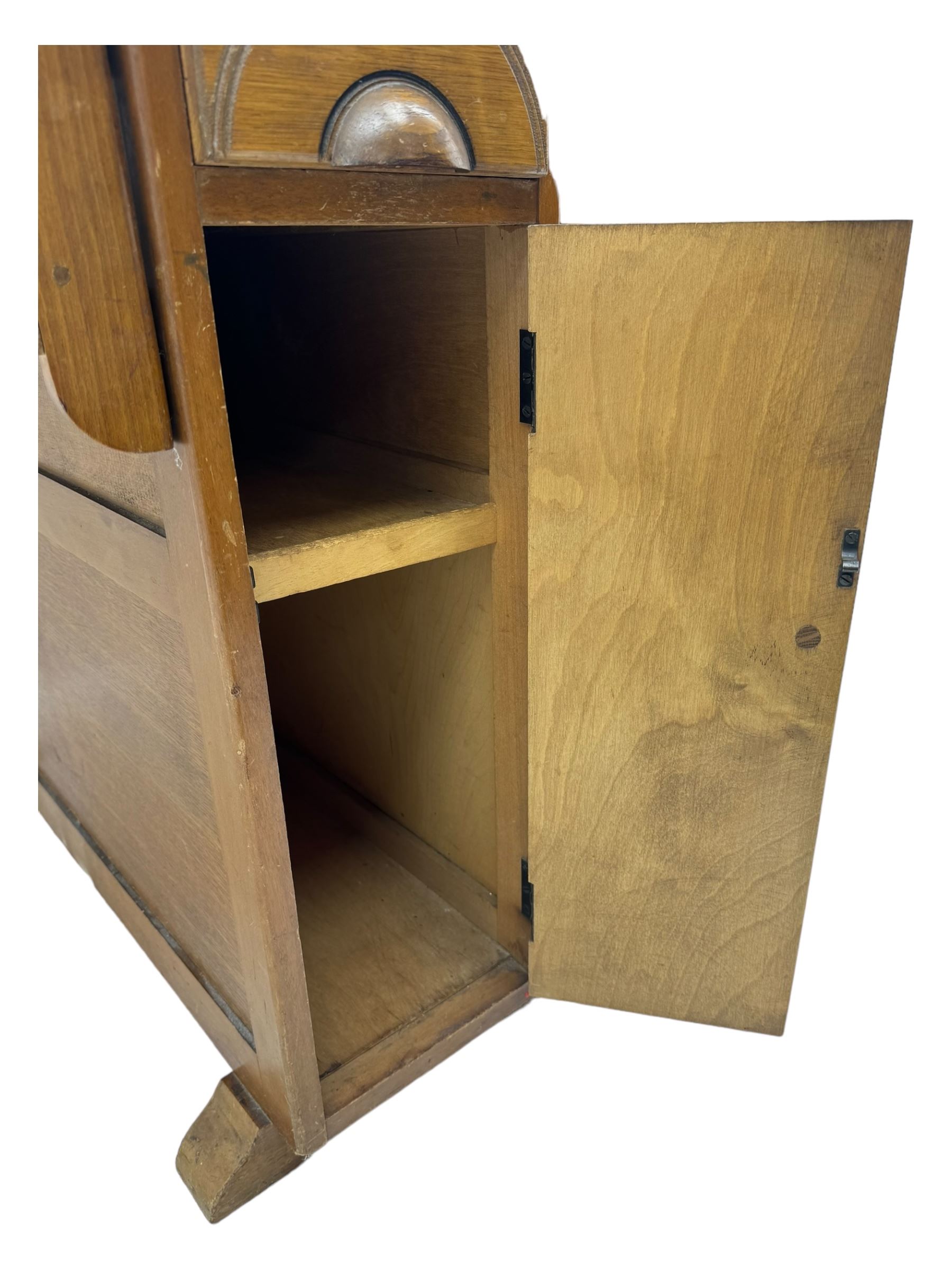 Early 20th century oak drop-leaf table, in the style of Harris Lebus, featuring rectangular top over central pedestal base, with two drawers and two cupboards, on gateleg supports