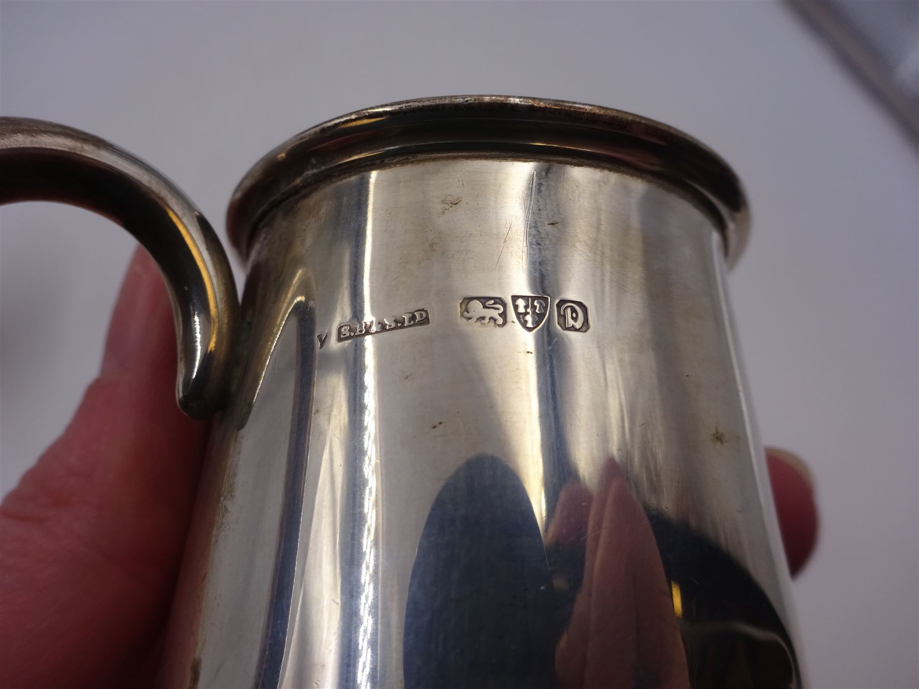 Two silver christening mugs, the first a Victorian example, of part fluted waisted form, upon circular foot with scroll handle, hallmarked Edward, John & William Barnard, London 1838, the second example of plain slightly tapering form with C handle, hallmarked S Blanckensee & Son Ltd, Chester 1929, tallest H9cm