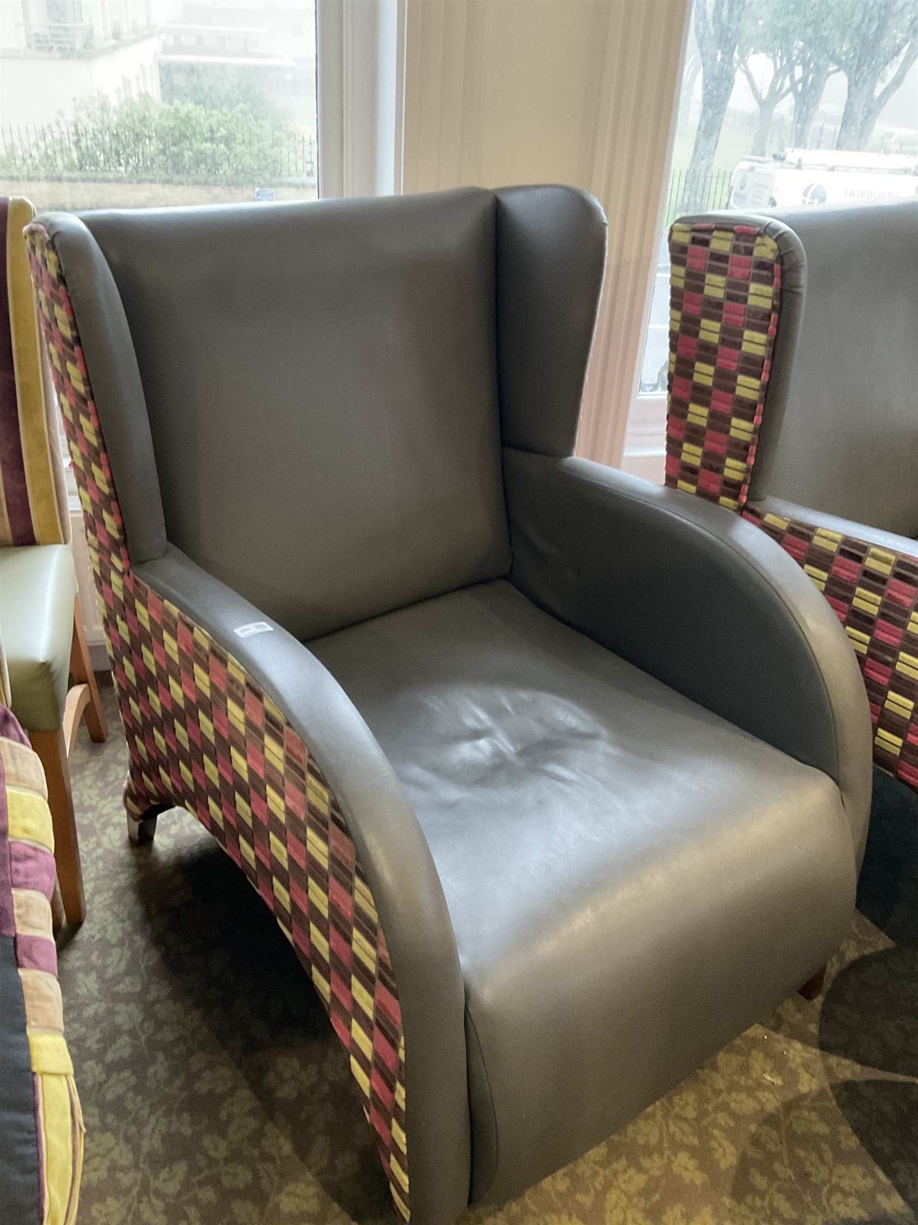 Two curved wing back armchairs, upholstered in charcoal and stripe