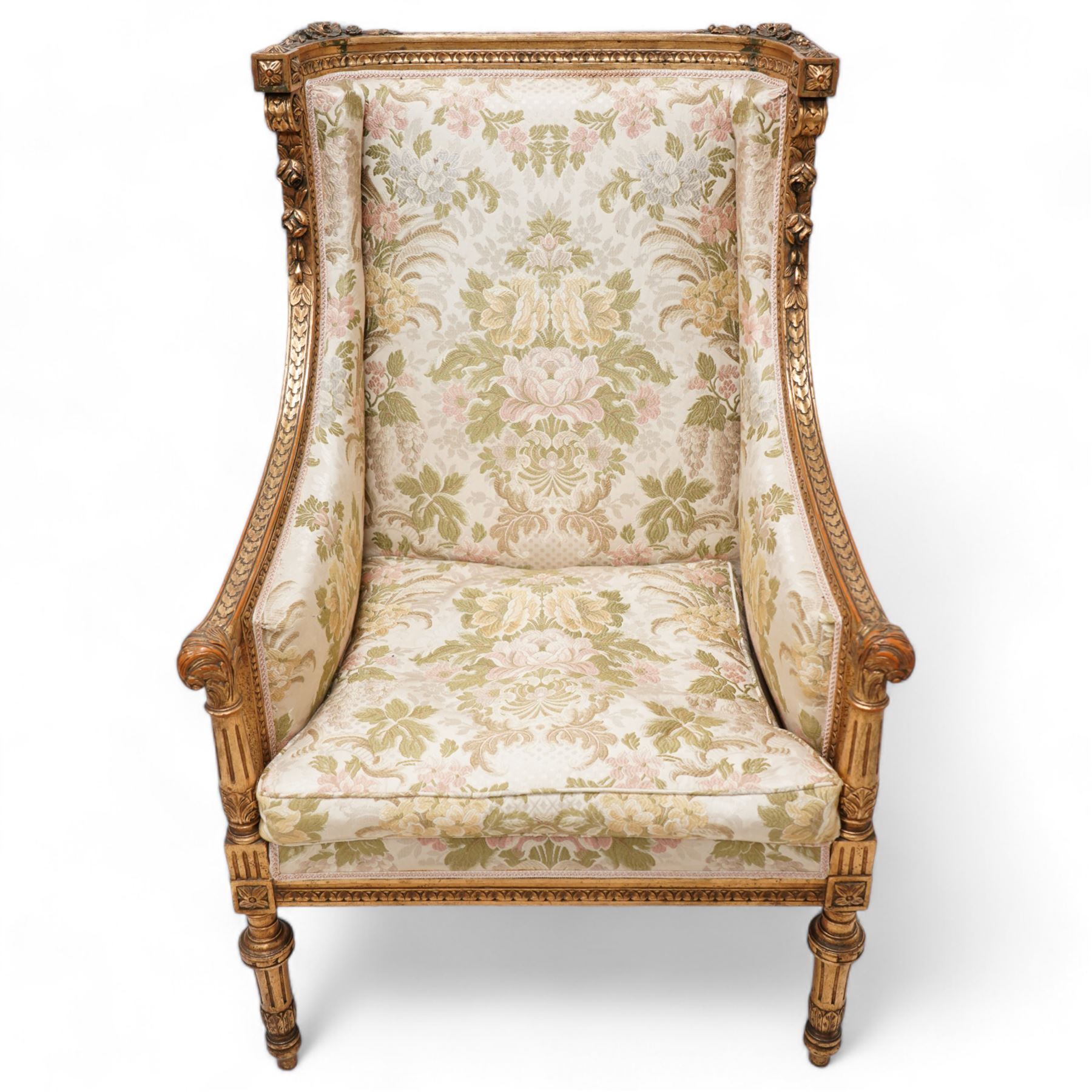 Late 19th century French gilt wood and gesso enclosed armchair, the cresting carved with floral bouquets over foliate moulding, upholstered in floral pattern fabric with repeating pattern, down-swept arms with scrolled acanthus leaf terminals, on turned and fluted feet carved with foliage 