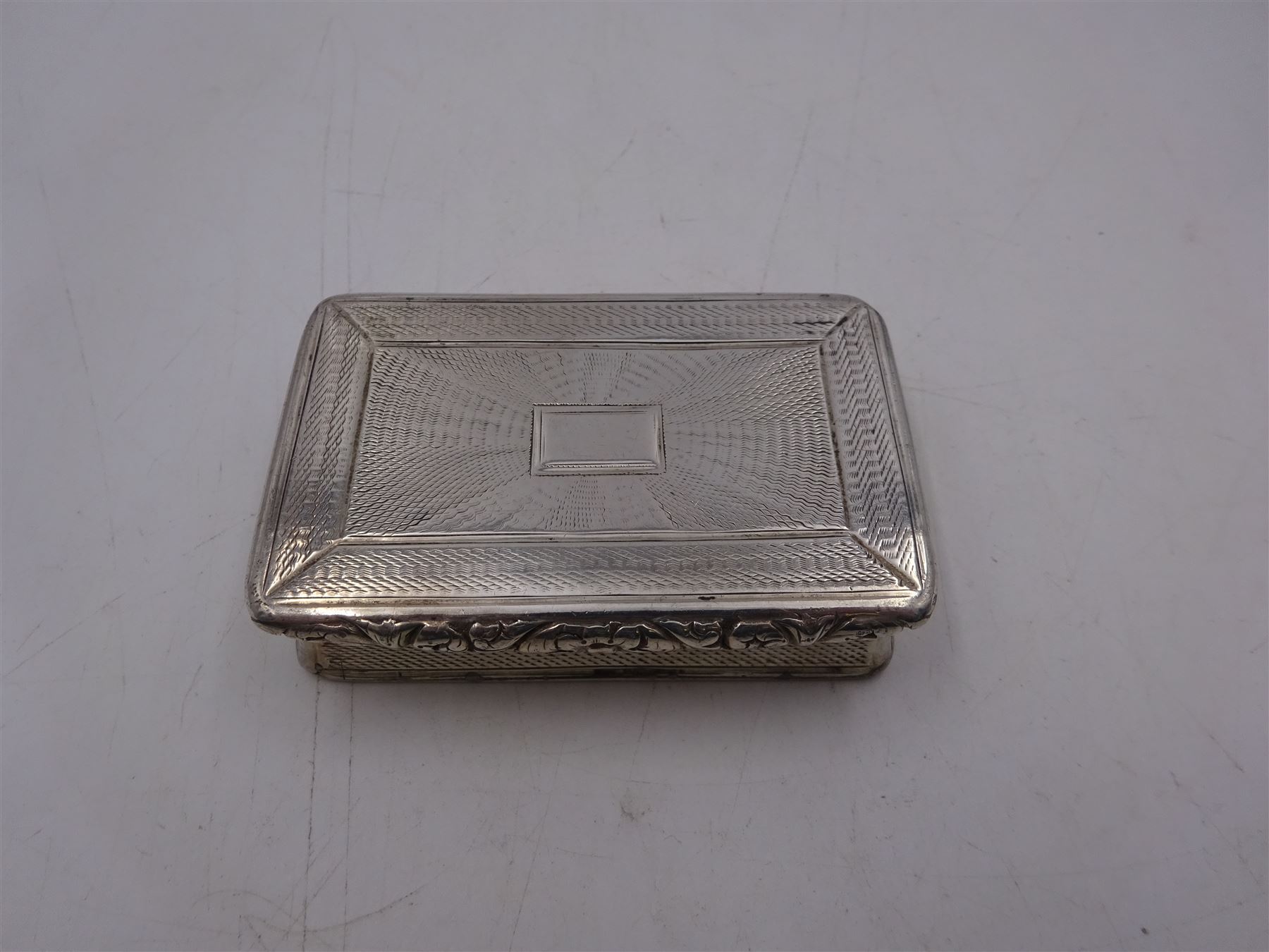 George IV silver snuff box, of rectangular form, with engine turned decoration, chased foliate borders and blank cartouche to centre of hinged cover, opening to reveal a gilt interior, hallmarked John Bettridge, Birmingham 1825, W7.6cm