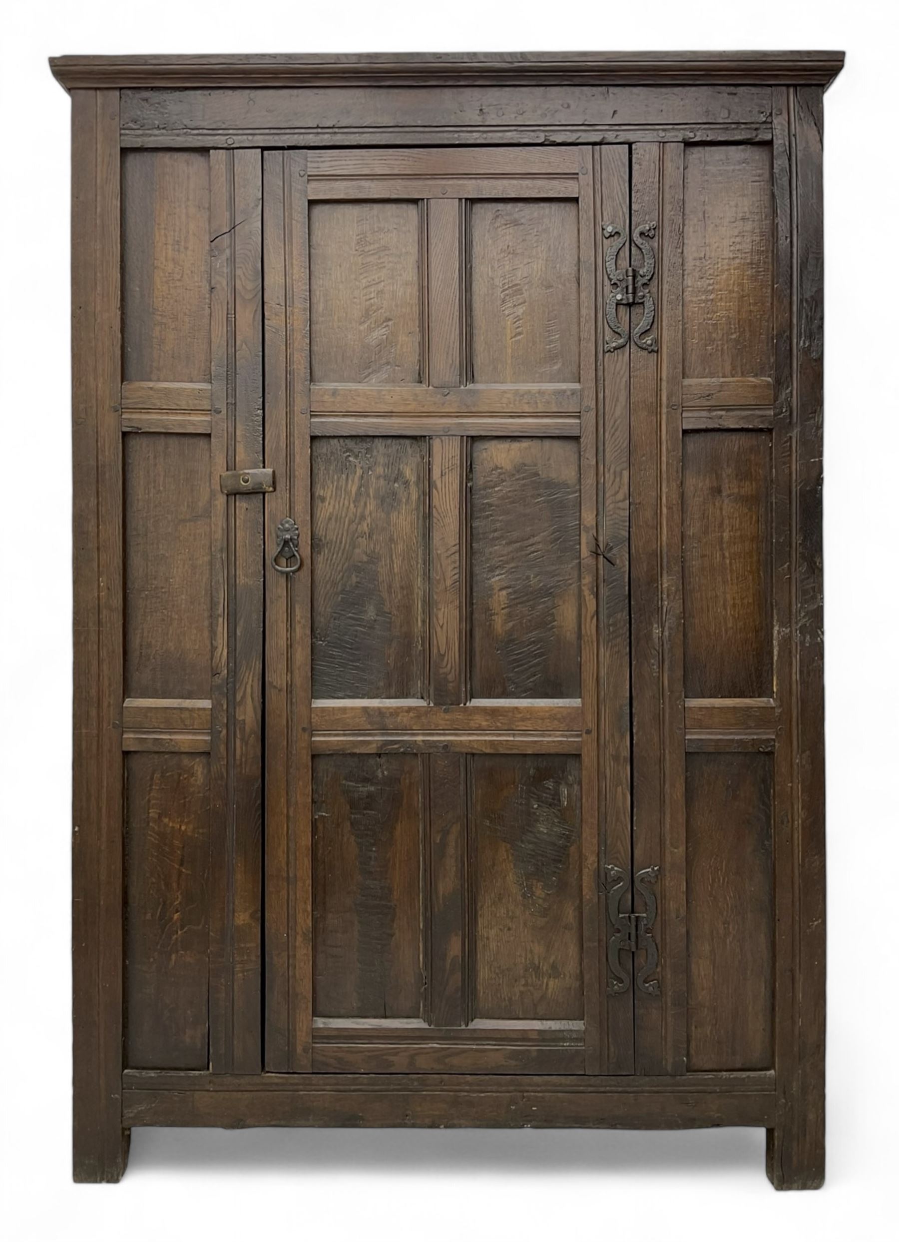 17th century and later oak hall cupboard, panelled front and sides with moulded frame, enclosed by single door with wrought metal hinges and handle, the interior fitted with hooks, on stile supports 