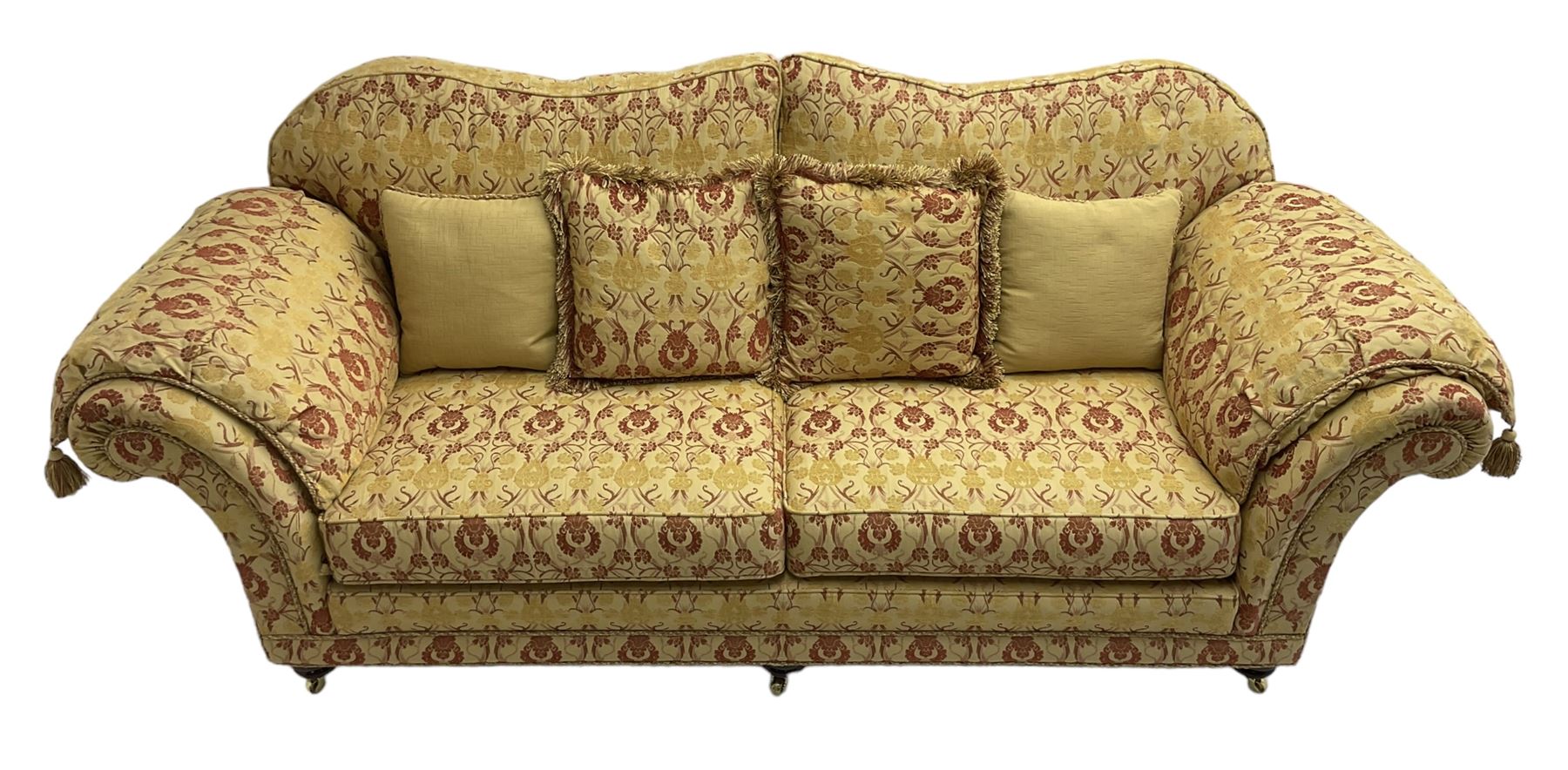 Steed Upholstery Ltd. - 'Lincoln' three-seat sofa upholstered in gold 'Olympia' floral pattern corded and tasselled fabric, together with scatter cushions and arm covers, on turned feet with brass castors