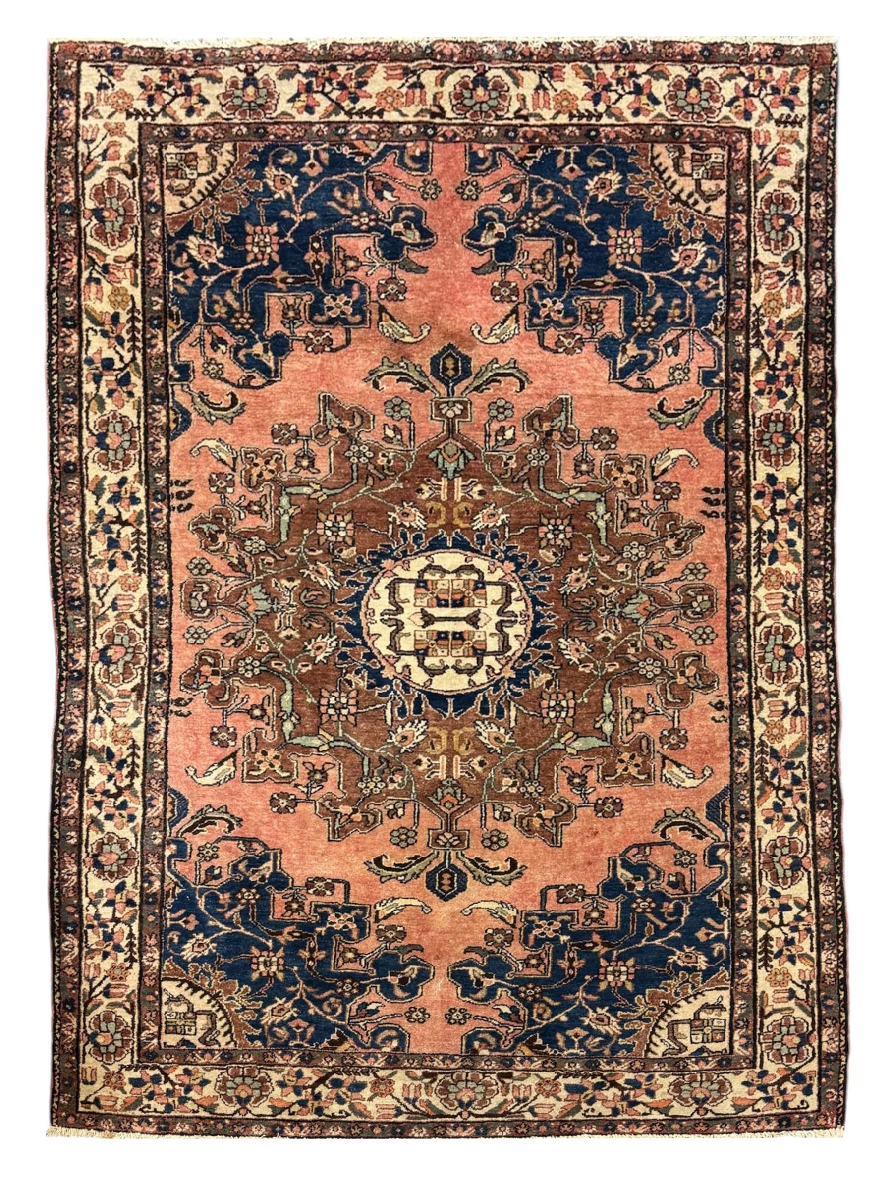 Persian Hamadan ground rug, central medallion design with a salmon pink field, accentuated by navy blue spandrels, surrounded by a stylised floral border in cream and blue tones