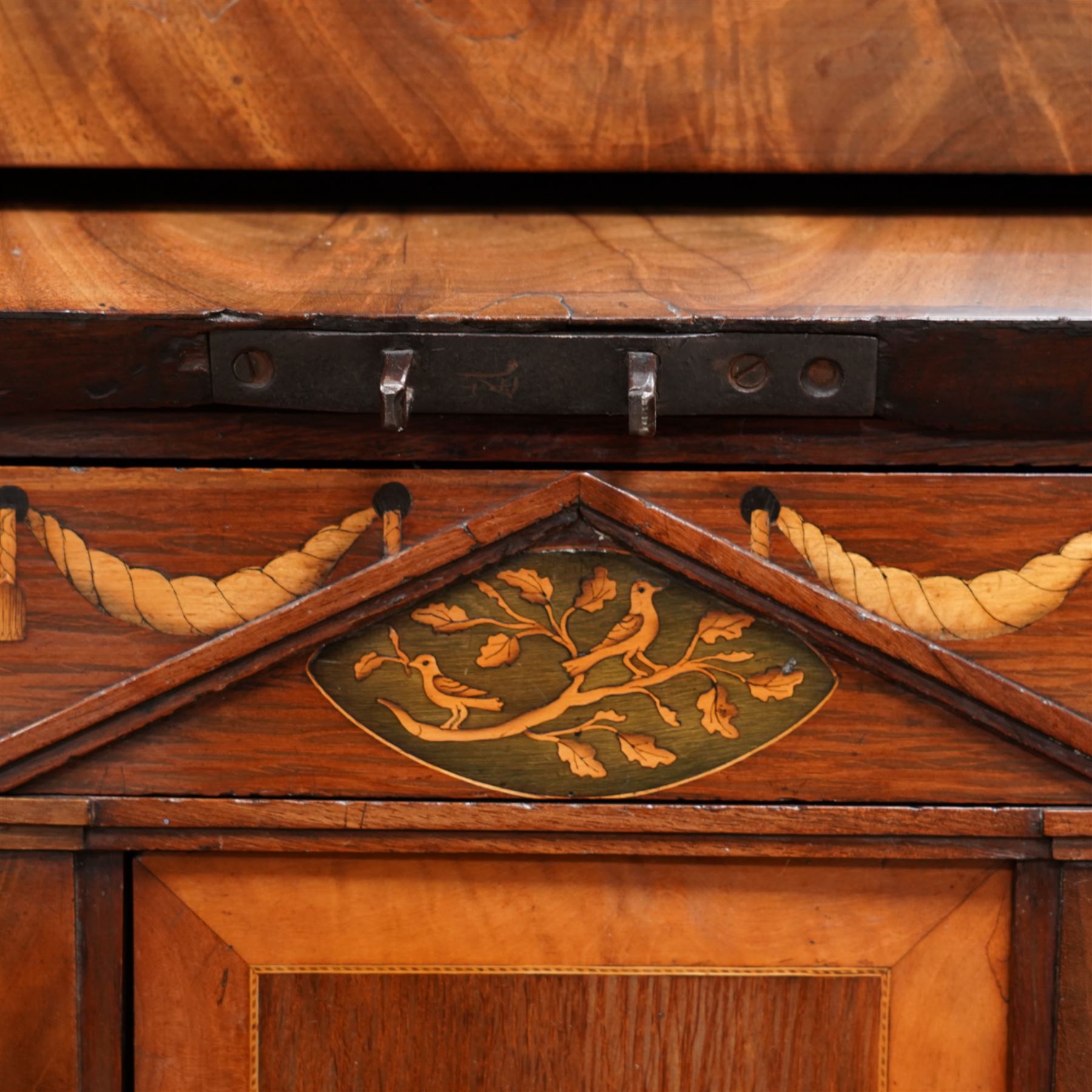 19th century Biedermeier figured mahogany cylinder bureau cabinet, the raised super structure with stepped pointed pediment over hidden cupboard and hinged fall front, the interior fitted with pigeonholes and secret drawers behind rusticated inlay, curved flanking cupboards fitted with internal drawers, the cylinder top opens to reveal small drawers, document divisions and secret compartments, sliding desk with central hinged writing surface, inlaid with satinwood bands and draped festoons, fitted with three long drawers, on bracket feet