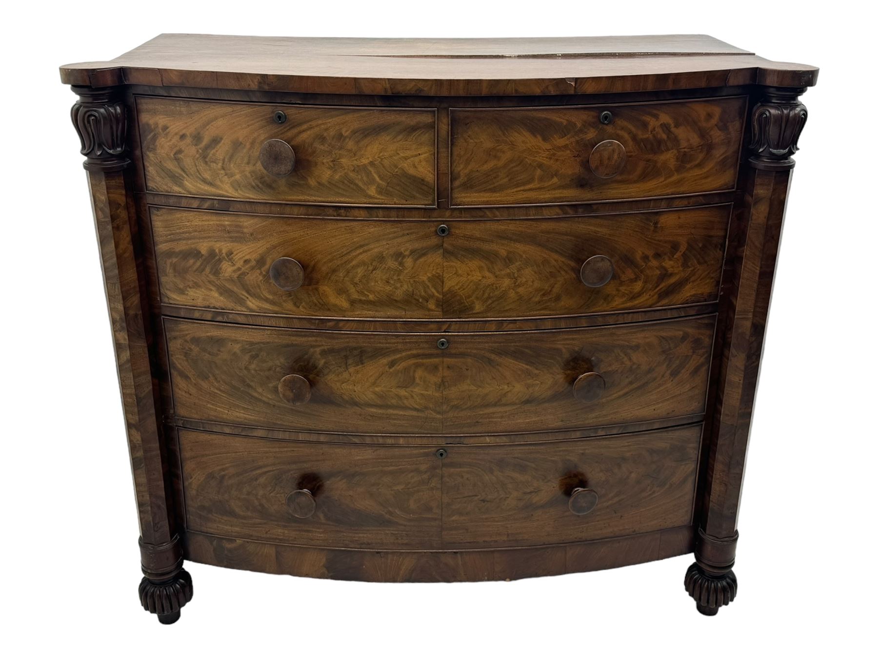 Early Victorian mahogany bow front chest, two short over three long graduating cockbeaded drawers, flanked by faceted columns with carved acanthus leaf capitals, standing on turned bun supports with fluted detailing