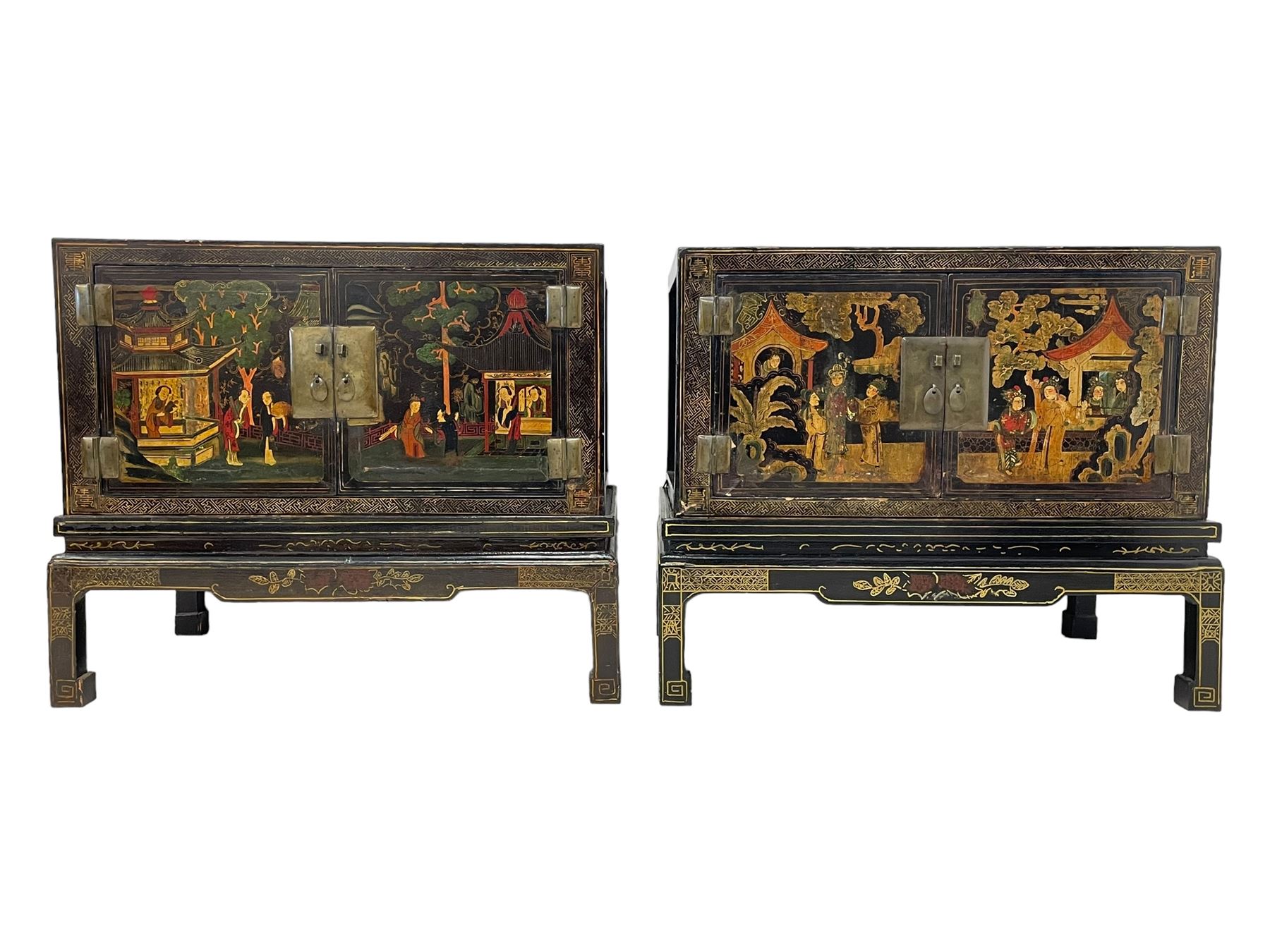 Pair of early 20th century Chinese ebonised and lacquered wood cabinets, the top decorated with dragons over lapping waves within a gilt patterned panel, the surrounding band decorated with Chinese symbols and flowerheads, enclosed by two doors each with village scenes with pagodas, figures and trees, the panelled sides decorated with a figure riding a dragon on stands with gilt decorated 