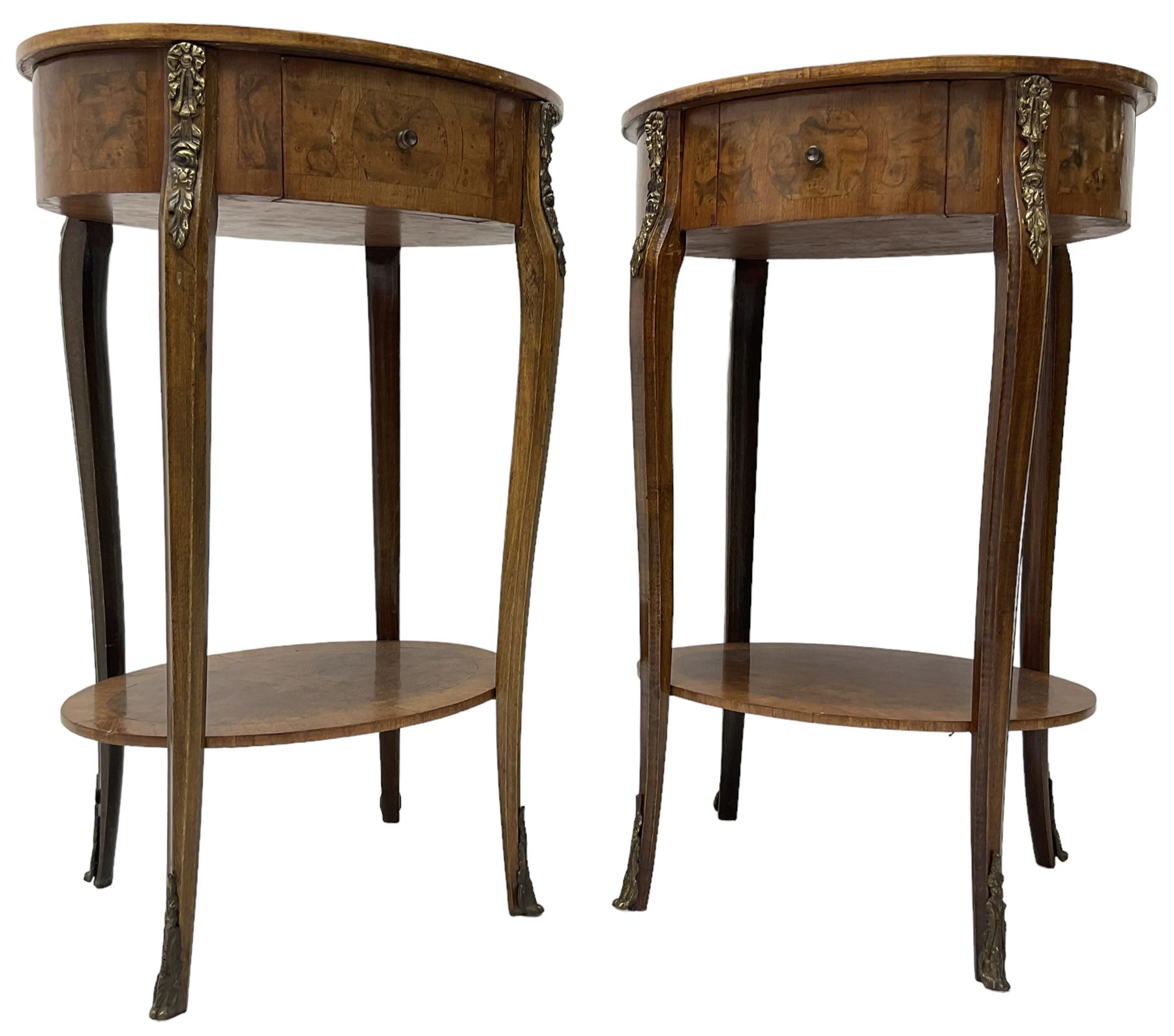 Pair of early 20th century French walnut bedside stands, oval bookmatched and cross-banded top fitted with single drawer, raised on cabriole supports united by undertier, decorated with floral gilt metal mounts